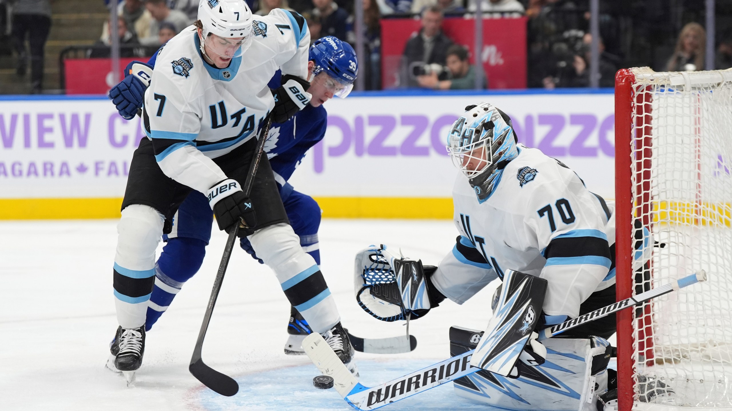 Utah Hockey Club goaltender Karel Vejmelka (70) makes a save as defenceman Michael Kesselring (7) and Toronto Maple Leafs centre Fraser Minten (39) battle for a rebound during the second period of an NHL hockey game in Toronto, Sunday, Nov. 24, 2024. (Frank Gunn/The Canadian Press via AP)