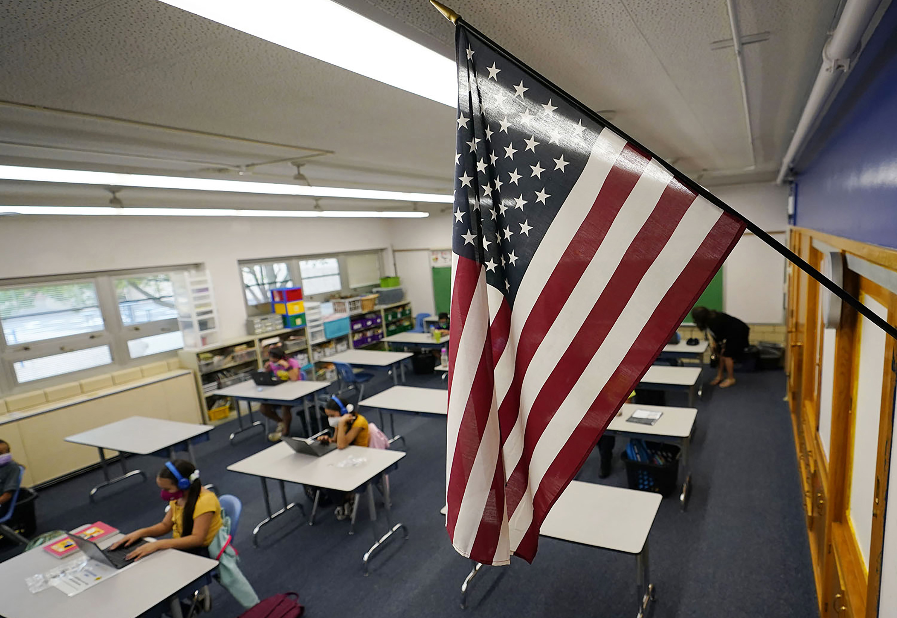 FILE - An American flag hangs in a classroom as students work on laptops in Newlon Elementary School, Aug. 25, 2020, in Denver. (AP Photo/David Zalubowski, File)