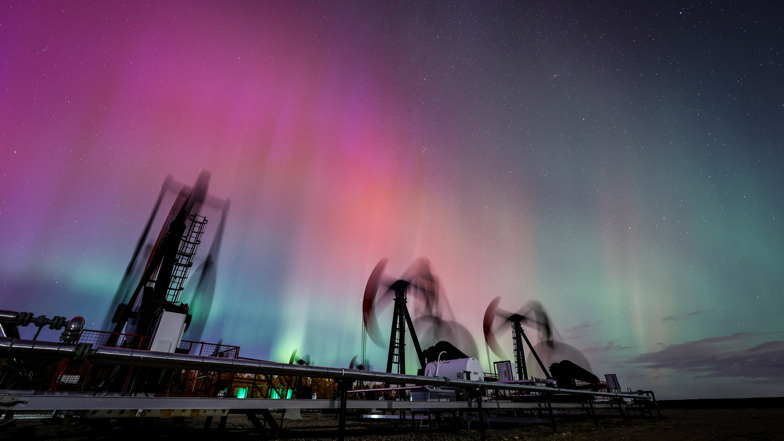 FILE - An aurora borealis, also known as the northern lights, makes an appearance over pumpjacks as they draw out oil and gas from well heads near Cremona, Alberta, Thursday, Oct. 10, 2024. (Jeff McIntosh/The Canadian Press via AP, File)