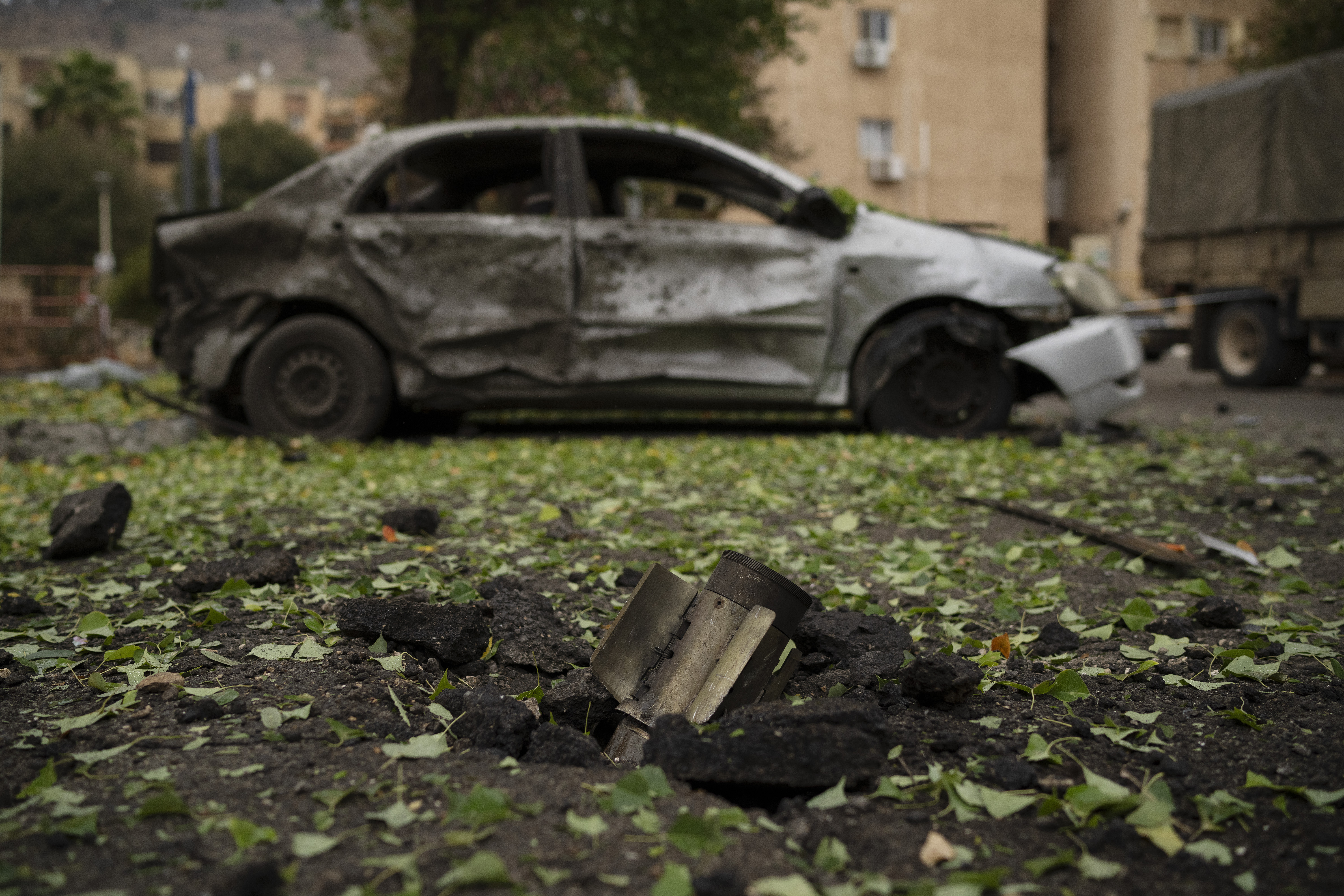 A rocket, fired from Lebanon during the night hours before the start of the ceasefire, sits wedged in the ground next to a damaged car in Kiryat Shmona, northern Israel, Wednesday, Nov. 27, 2024. (AP Photo/Leo Correa)