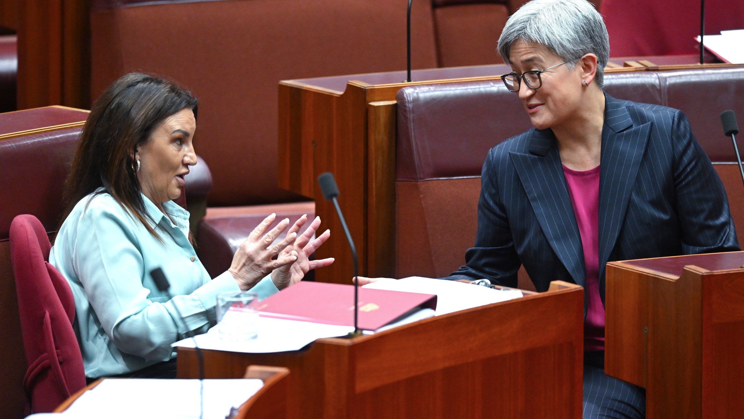 Senator Jacqui Lambie, left, gestures as she speaks to Australian Foreign Minister Penny Wong during debate in the Senate chamber at Parliament House in Canberra, Australia, Thursday, Nov. 28, 2024. (Lukas Coch/AAP Image via AP)