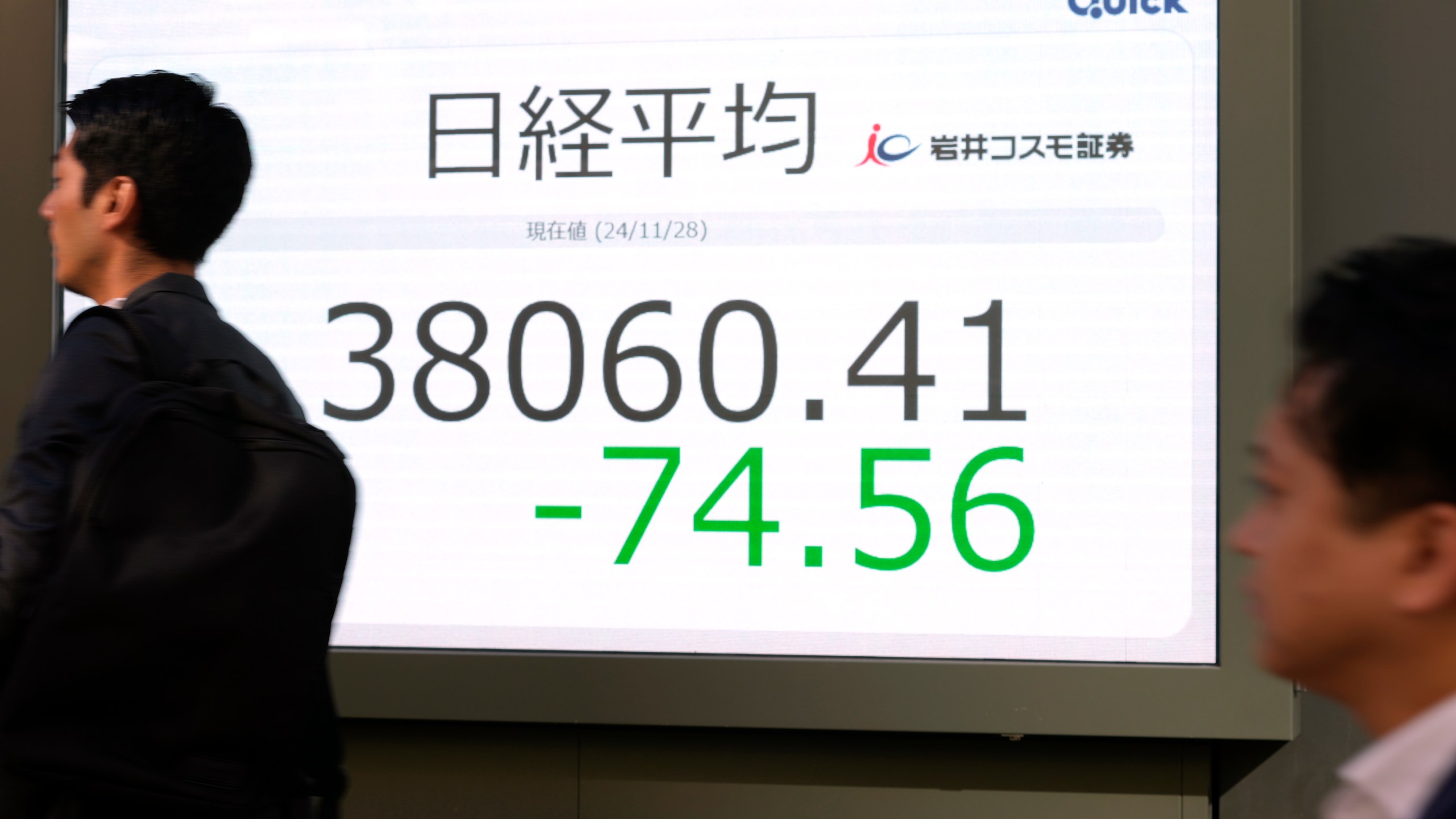 People walk past an electronic stock board showing Japan's Nikkei 225 stock index at a securities firm, Thursday, Nov. 28, 2024 in Tokyo. (AP Photo/Shuji Kajiyama)