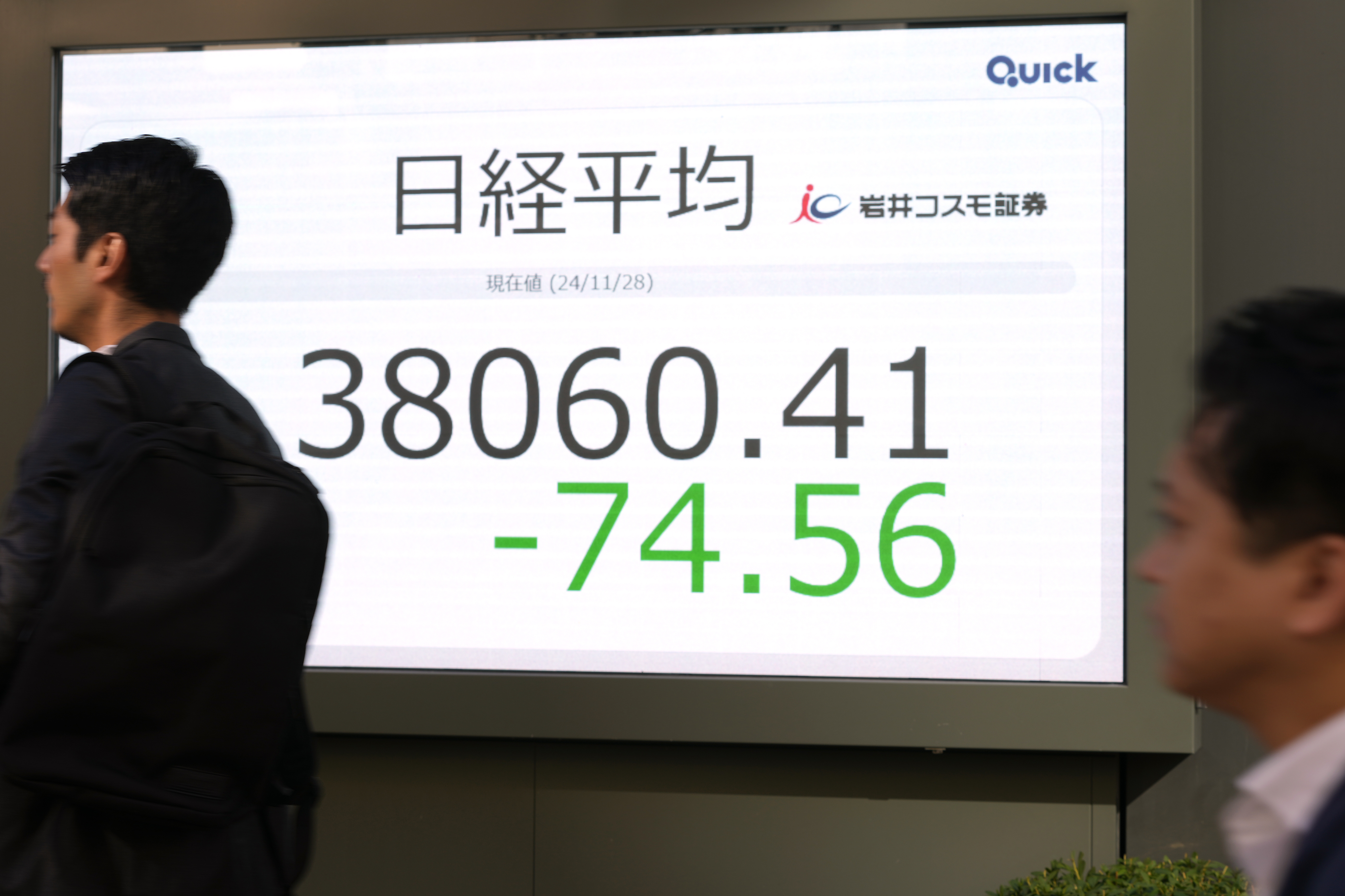 People walk past an electronic stock board showing Japan's Nikkei 225 stock index at a securities firm, Thursday, Nov. 28, 2024 in Tokyo. (AP Photo/Shuji Kajiyama)