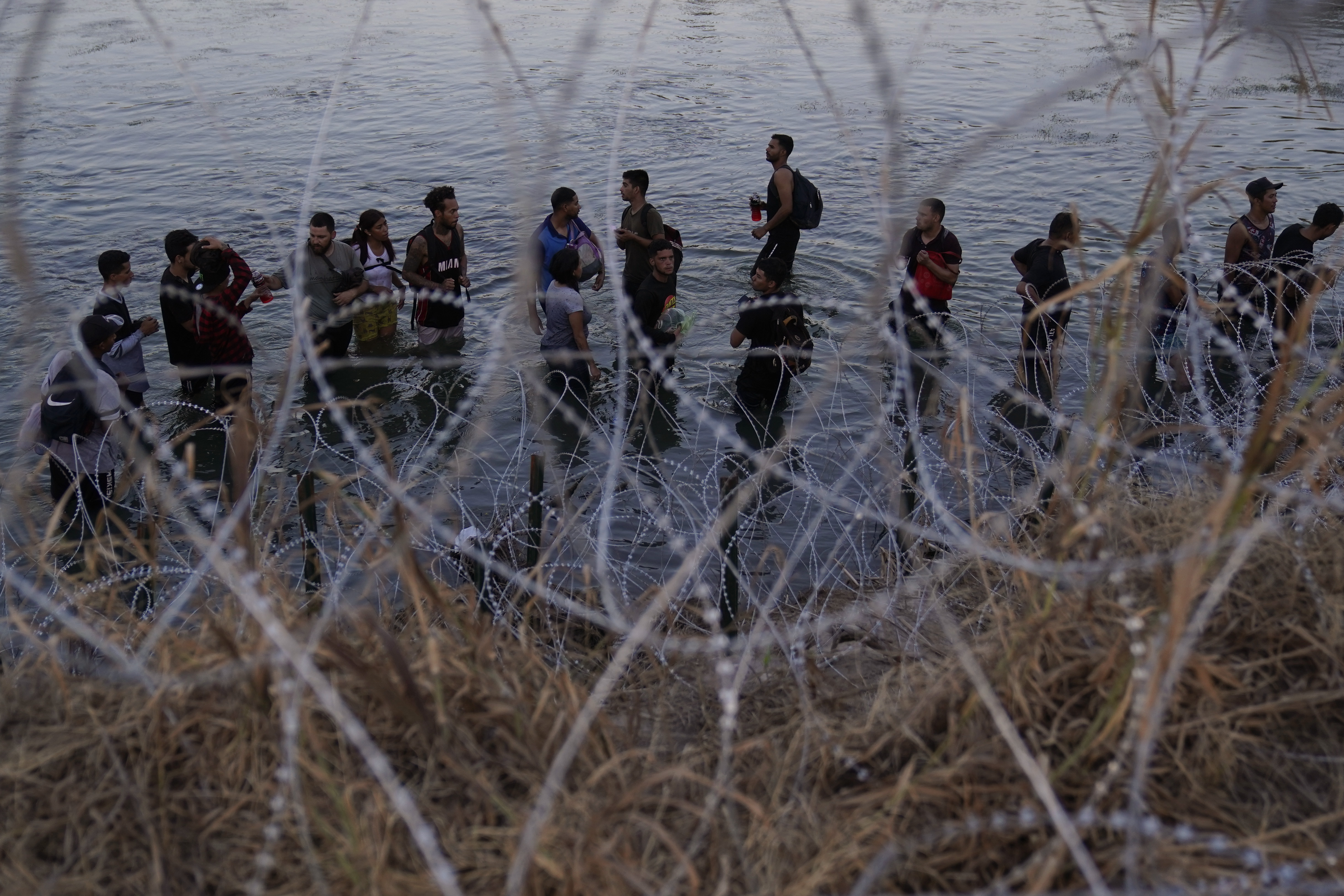 FILE - Migrants wait to climb over concertina wire after they crossed the Rio Grande and entered the U.S. from Mexico, Sept. 23, 2023, in Eagle Pass, Texas. (AP Photo/Eric Gay, File)