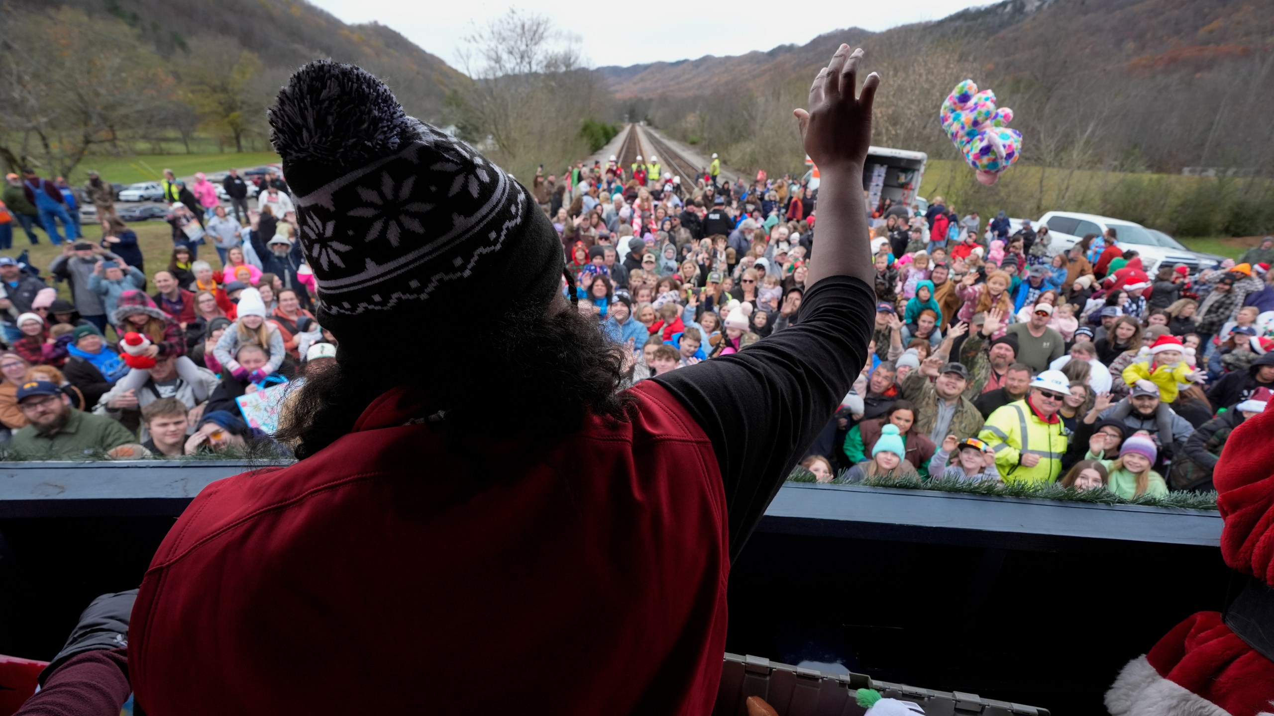 A volunteer tosses toys to people during the 82nd run of the CSX Santa Train, Saturday, Nov. 23, 2024, in Kermit, Va. (AP Photo/George Walker IV)