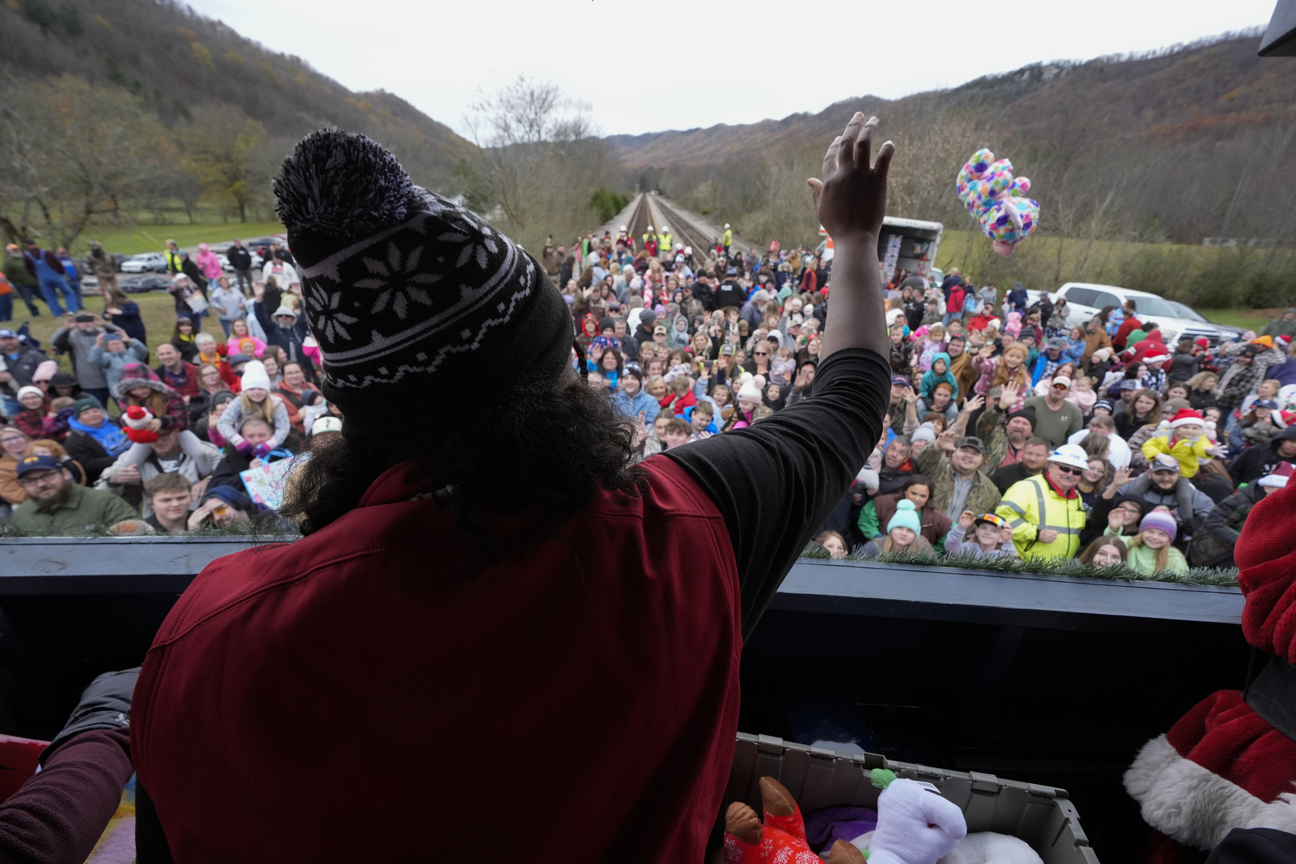 A volunteer tosses toys to people during the 82nd run of the CSX Santa Train, Saturday, Nov. 23, 2024, in Kermit, Va. (AP Photo/George Walker IV)