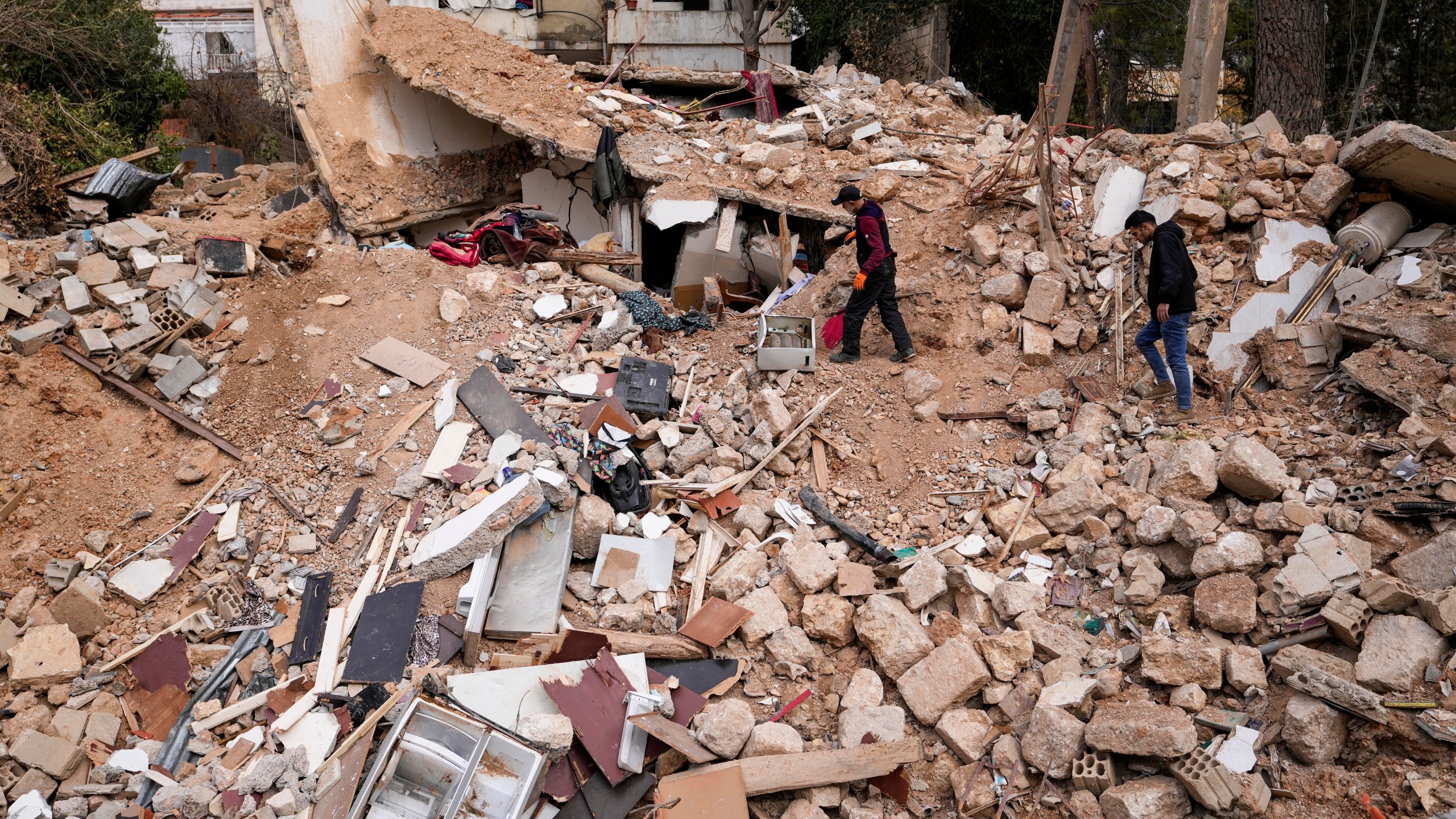 Displaced residents walk on the rubble of their destroyed house in Baalbek, eastern Lebanon, Thursday, Nov. 28, 2024. (AP Photo/Hassan Ammar)