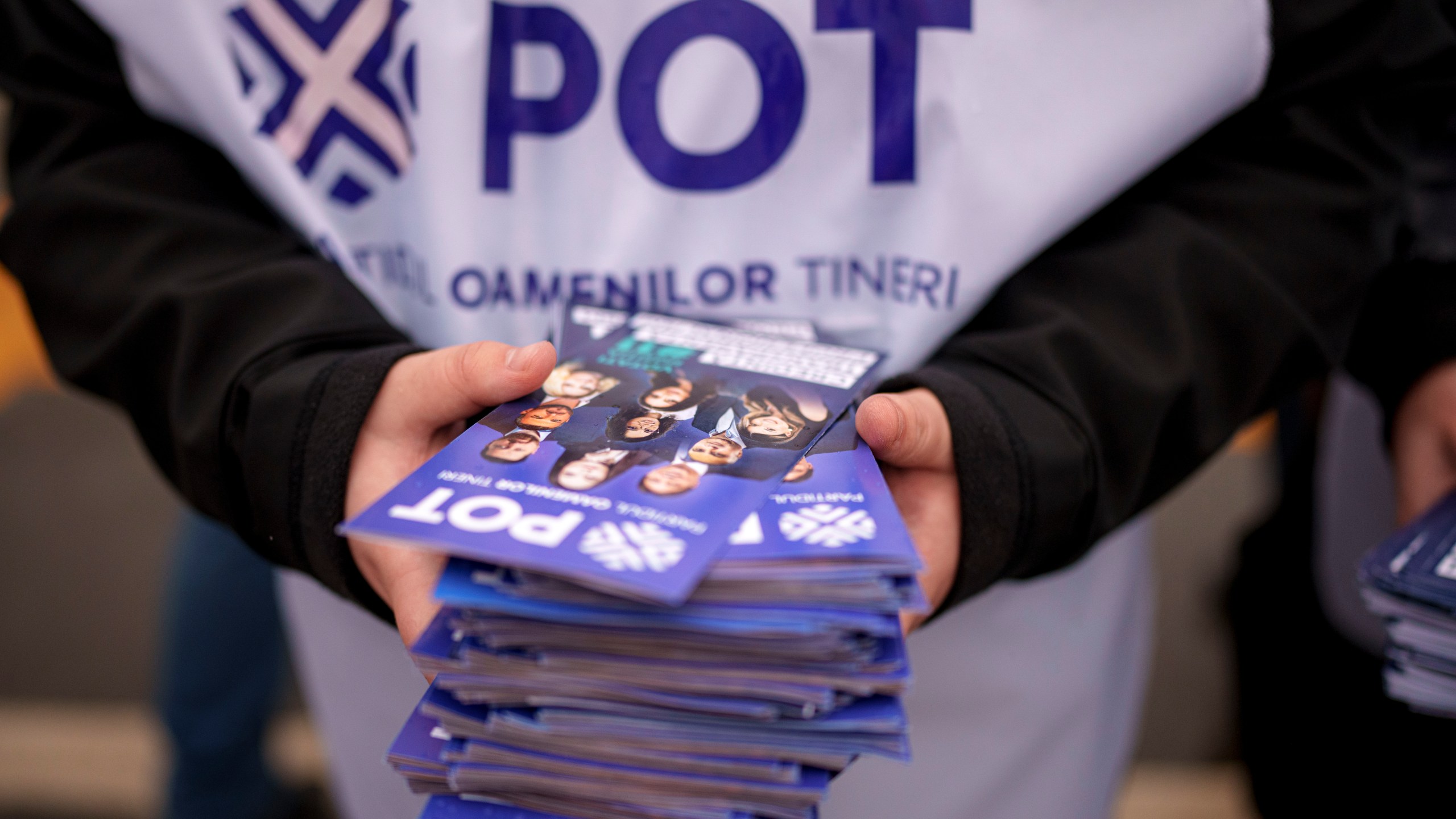 A man distributes leaflets of the Young People's Party or POT, which has backed Calin Georgescu, an independent candidate who won the first round of presidential elections, in Bucharest, Romania, Friday, Nov. 29, 2024. (AP Photo/Andreea Alexandru)