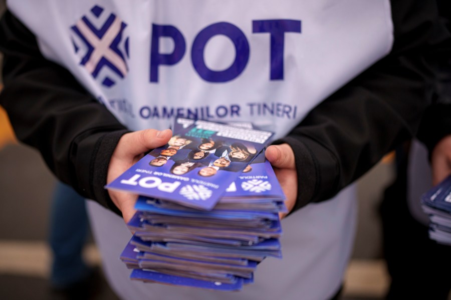 A man distributes leaflets of the Young People's Party or POT, which has backed Calin Georgescu, an independent candidate who won the first round of presidential elections, in Bucharest, Romania, Friday, Nov. 29, 2024. (AP Photo/Andreea Alexandru)