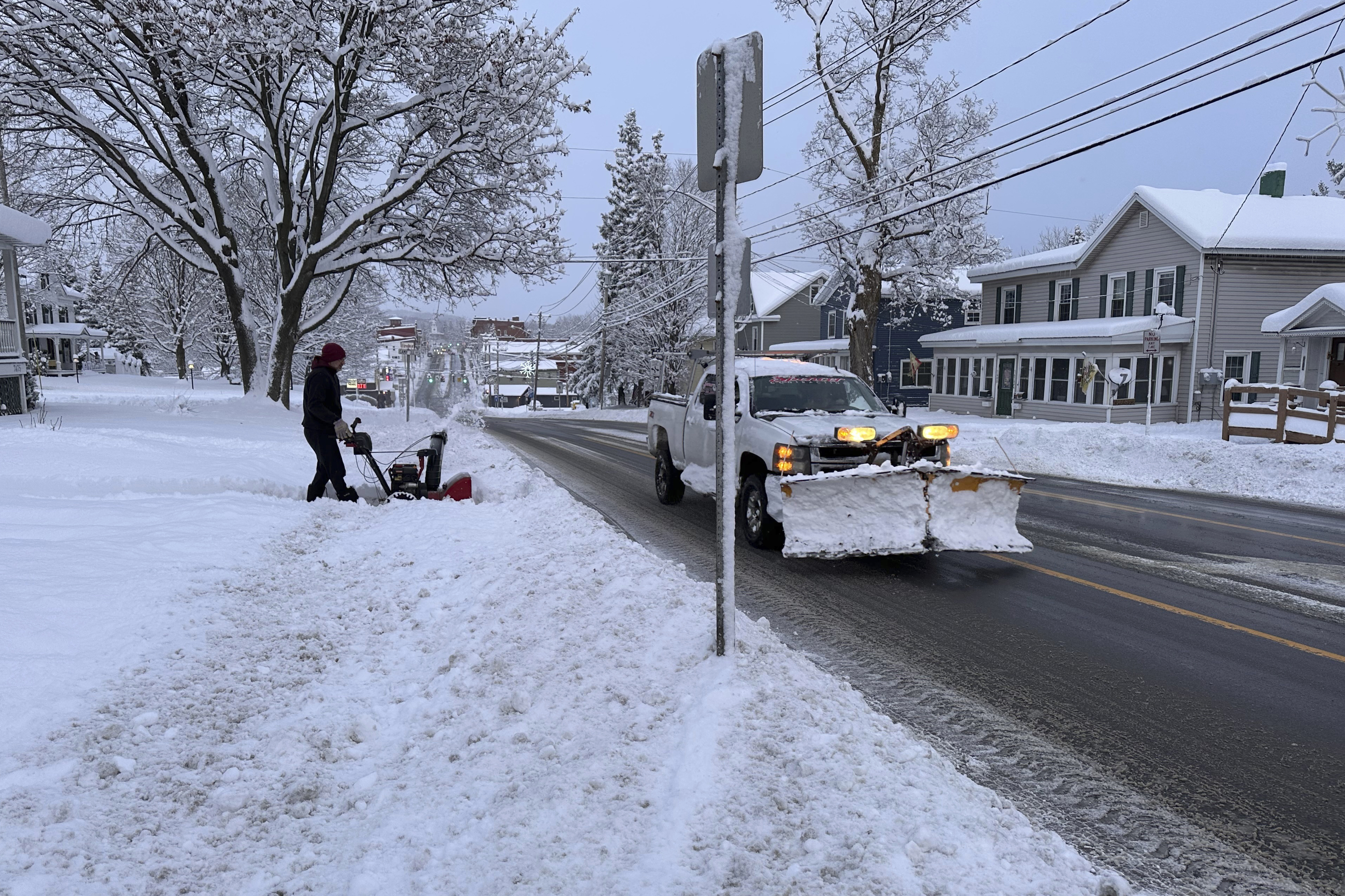 A person clears the snow from the sidewalk in Lowville, N.Y., on Saturday, Nov. 30, 2024. (AP Photo/Cara Anna)