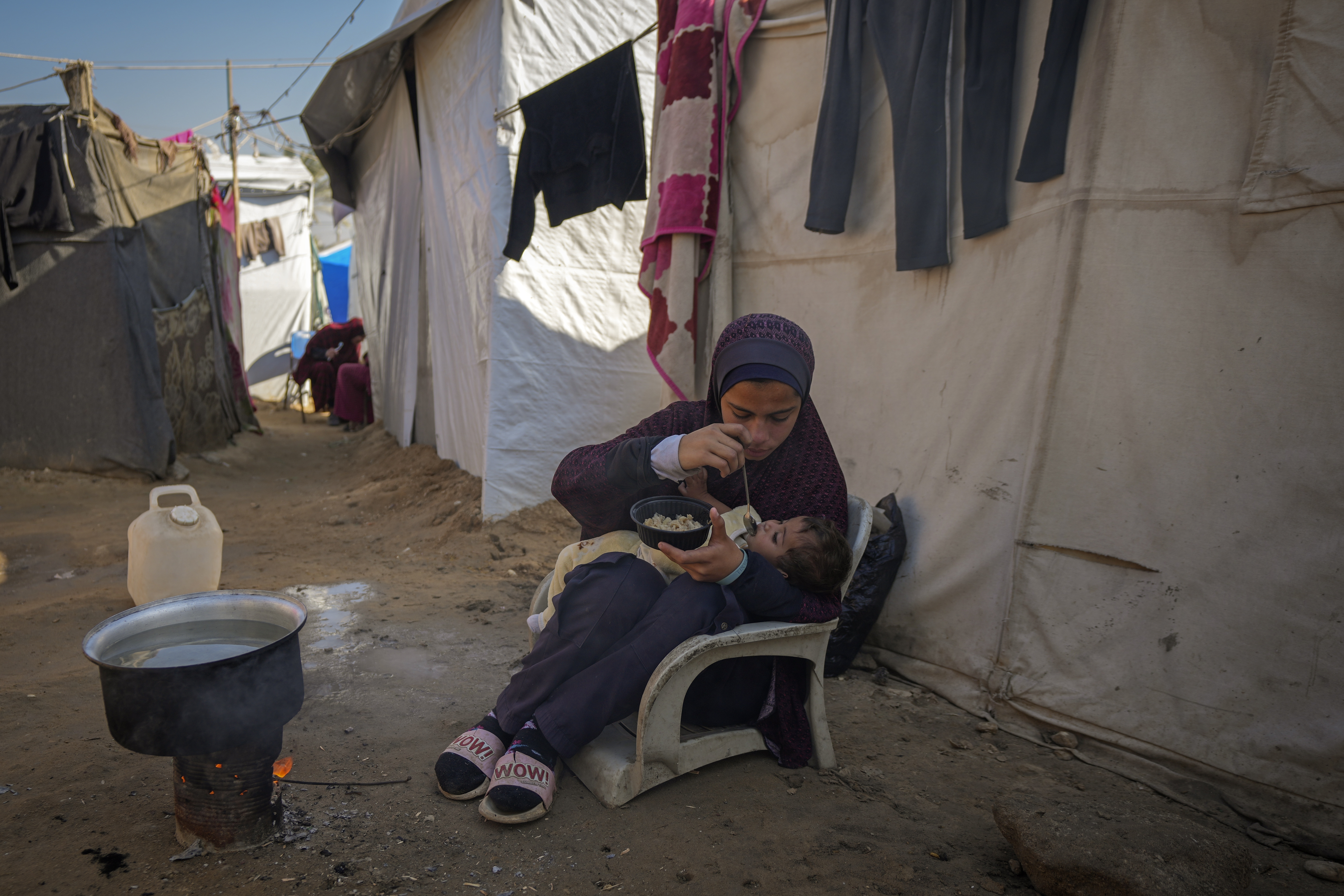 Asma Al-Kharobi, 16, feeds her 10-month-old baby sister bread mixed with water at a camp for displaced Palestinians in Deir al-Balah, Gaza Strip, on Sunday, Dec. 1, 2024. (AP Photo/Abdel Kareem Hana)