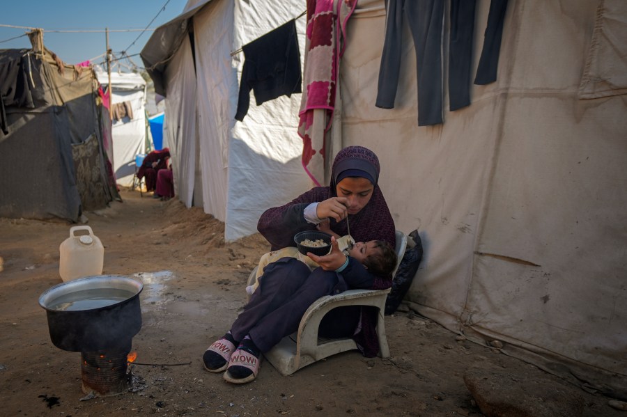 Asma Al-Kharobi, 16, feeds her 10-month-old baby sister bread mixed with water at a camp for displaced Palestinians in Deir al-Balah, Gaza Strip, on Sunday, Dec. 1, 2024. (AP Photo/Abdel Kareem Hana)