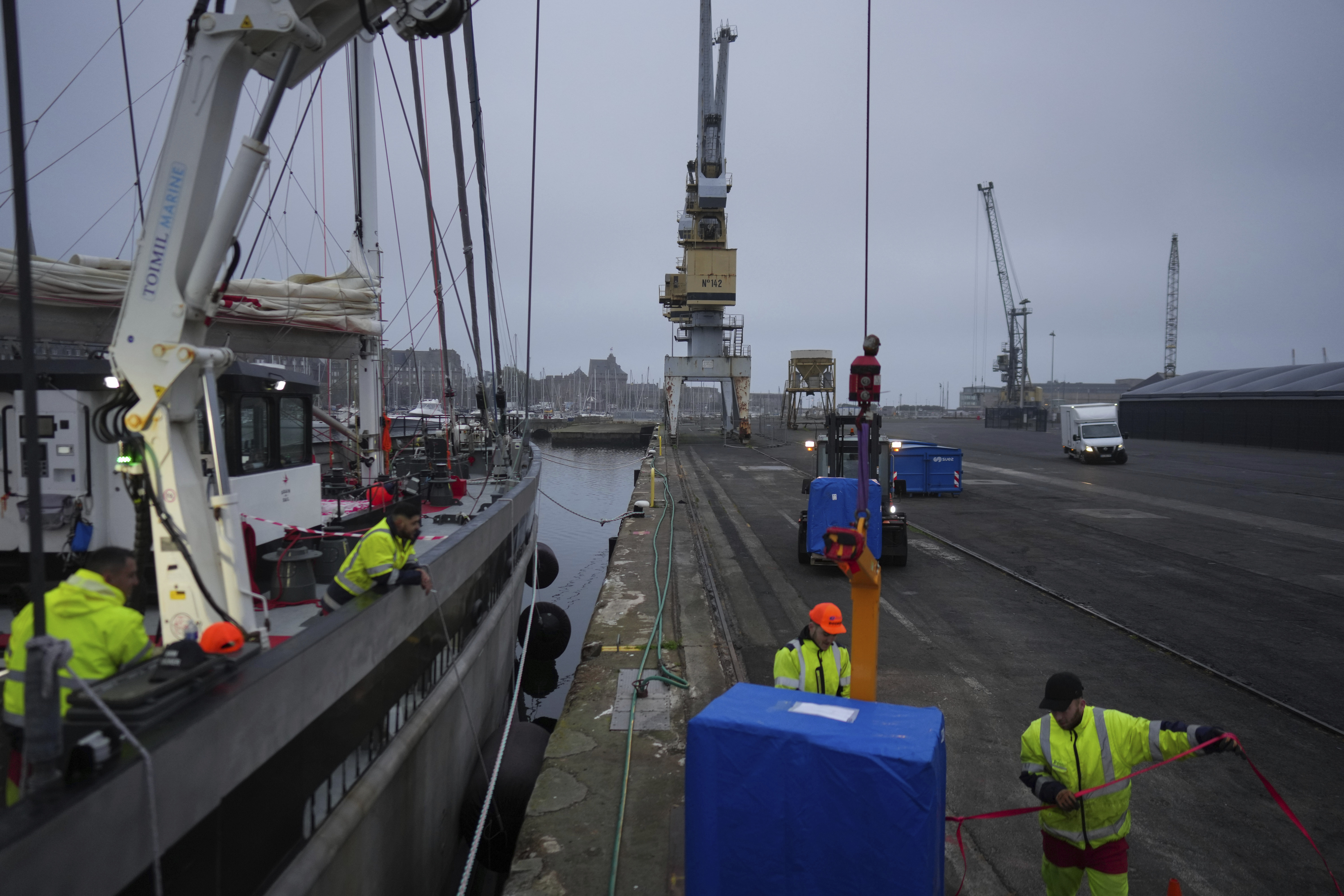 Dockers load pallets onto the sailboat 'Grain de Sail II' at the port of Saint Malo, western France, Nov. 8, 2024. (AP Photo/Thibault Camus)