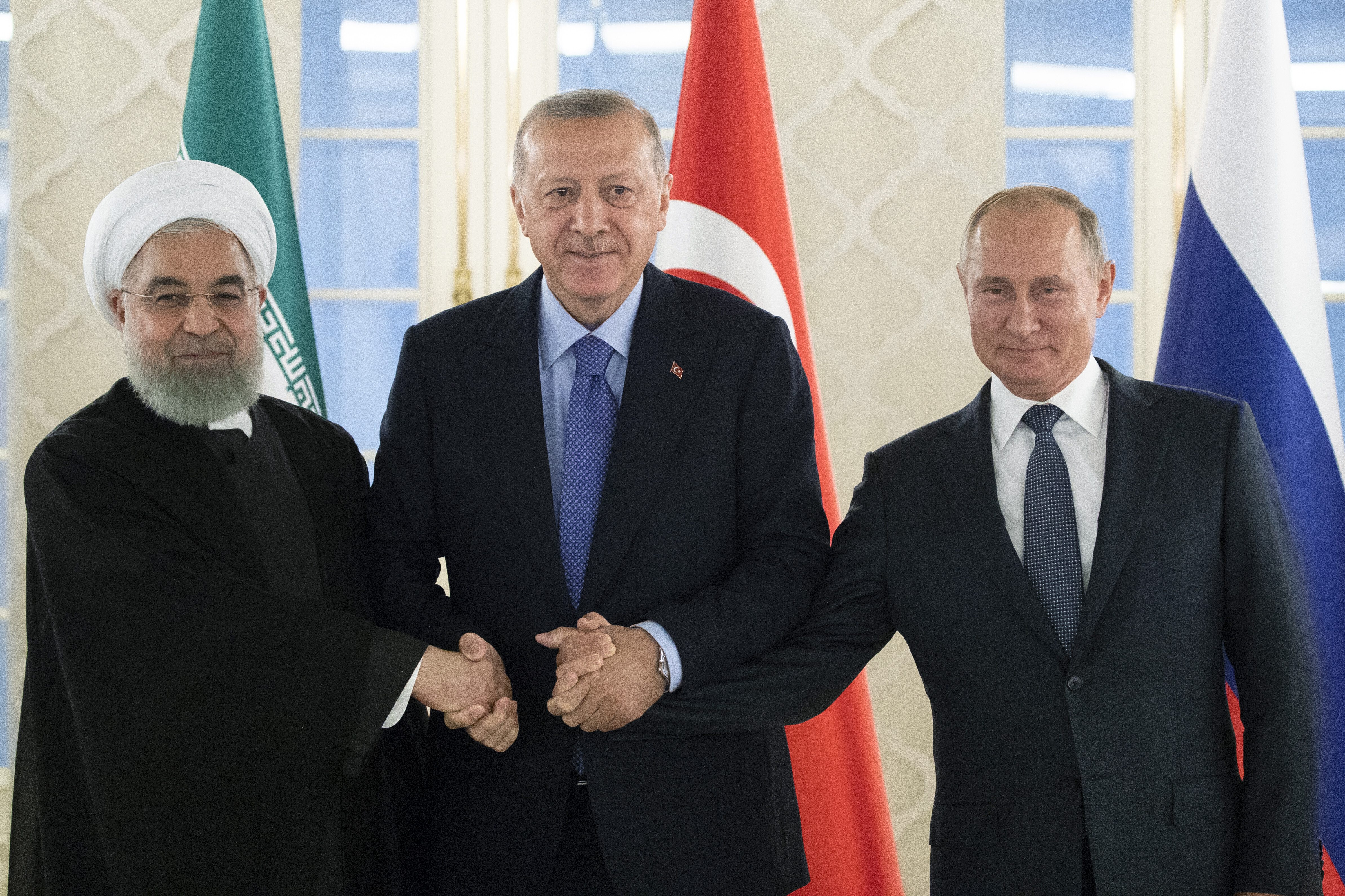 FILE - From left: Iranian President Hassan Rouhani, Turkish President Recep Tayyip Erdogan and Russian President Vladimir Putin shake hands during their meeting in Ankara, Turkey, Monday, Sept. 16, 2019. (AP Photo/Pavel Golovkin, Pool, File)