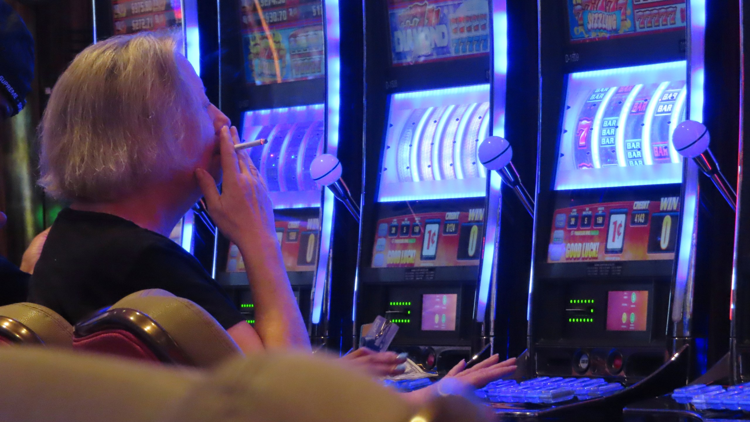 A gambler smokes while playing a slot machine at the Hard Rock casino in Atlantic City N.J. on Aug. 8, 2022. (AP Photo/Wayne Parry)