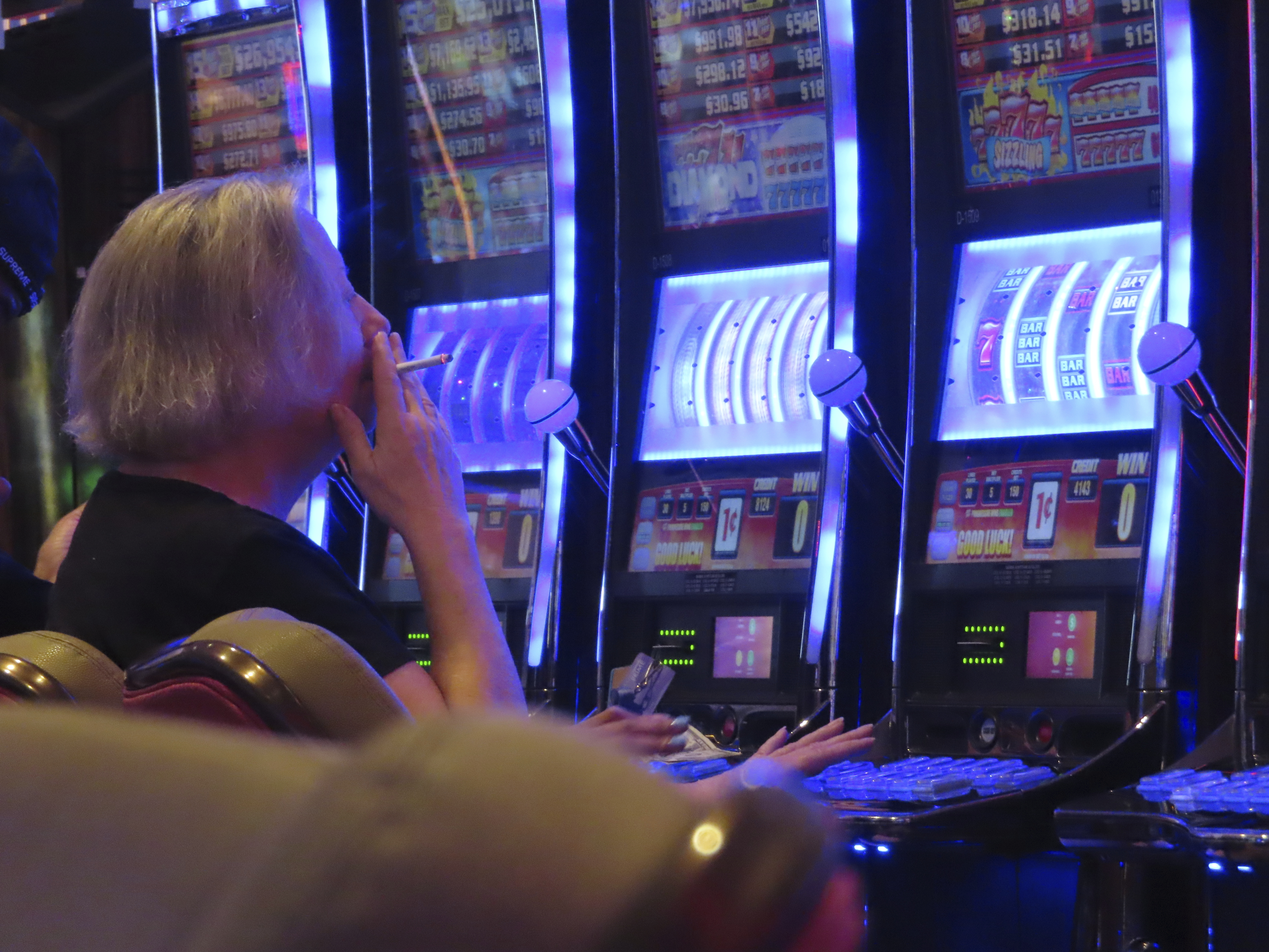 A gambler smokes while playing a slot machine at the Hard Rock casino in Atlantic City N.J. on Aug. 8, 2022. (AP Photo/Wayne Parry)