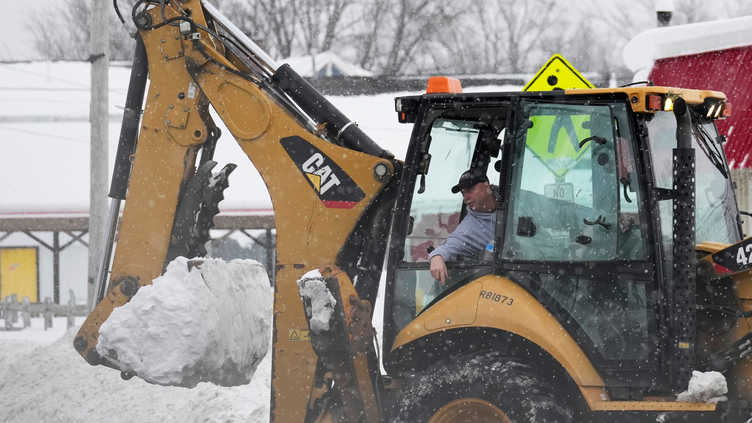 Dwayne Bennett, mayor of Geneva-on-the-Lake, drives a heavy equipment to clear snow as more snow falls Monday, Dec. 2, 2024, in Geneva-on-the-Lake, Ohio. (AP Photo/Sue Ogrocki)