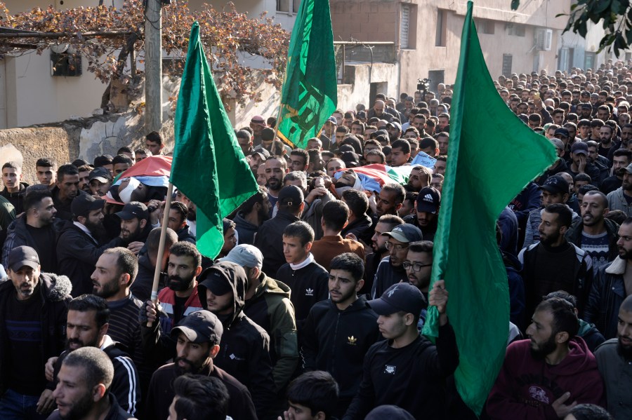 Mourners carry Hamas flags and the bodies, wrapped with the Palestinian flag, of Akram Abu Arrah and Mohammad Ghannam, both killed in an airstrike Israel said targeted a militant cell, during their funeral in the West Bank village of Al-Aqaba, Tuesday Dec. 3, 2024. (AP Photo/Majdi Muhammad)