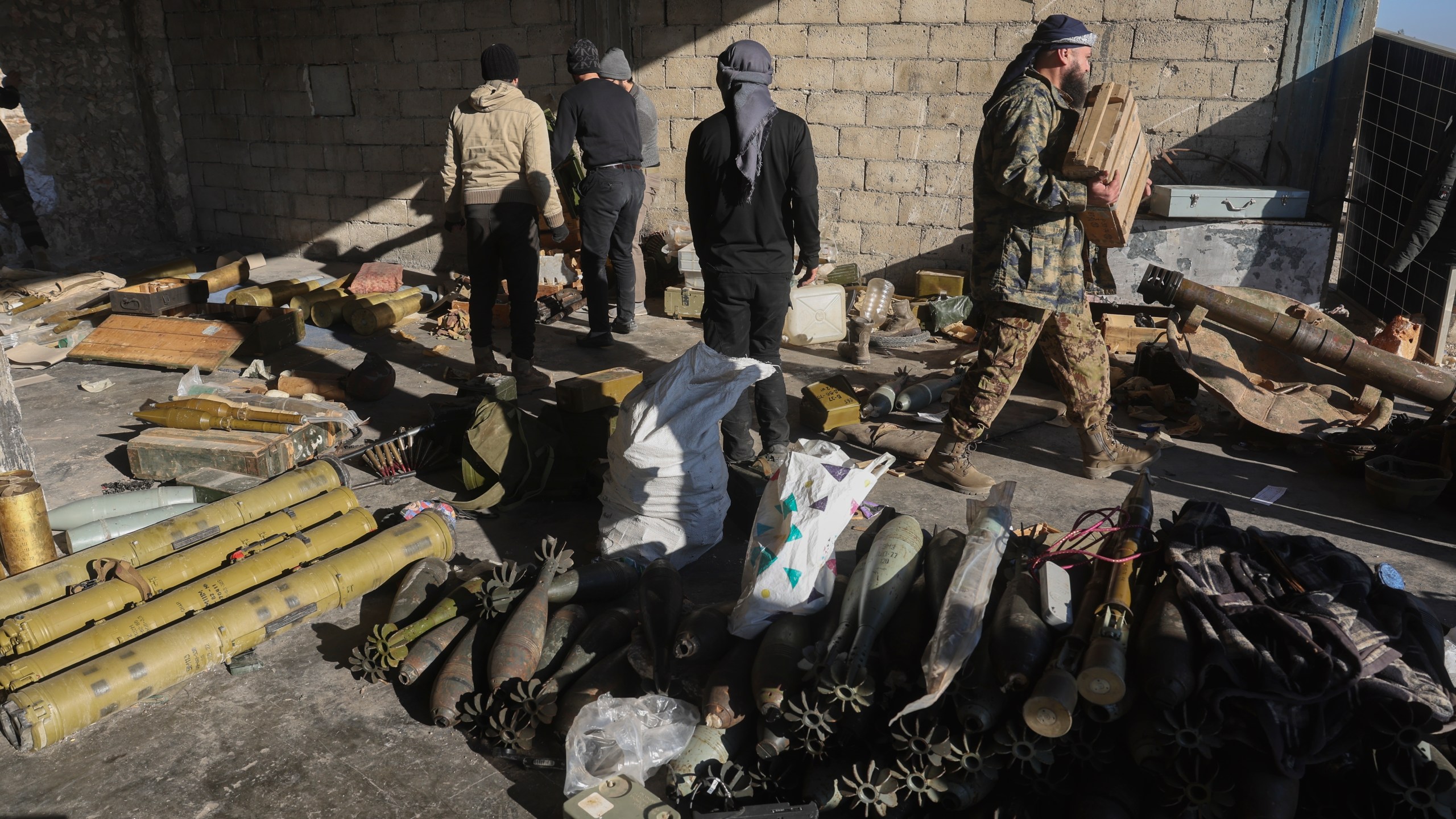 Syrian opposition fighters seize ammunition abandoned by the army in the town of Khan Assubul, Syria, southwest of Aleppo, Sunday, Dec. 1, 2024. Insurgents launched a two-pronged attack on Aleppo and the countryside around Idlib. (AP Photo/Ghaith Alsayed)