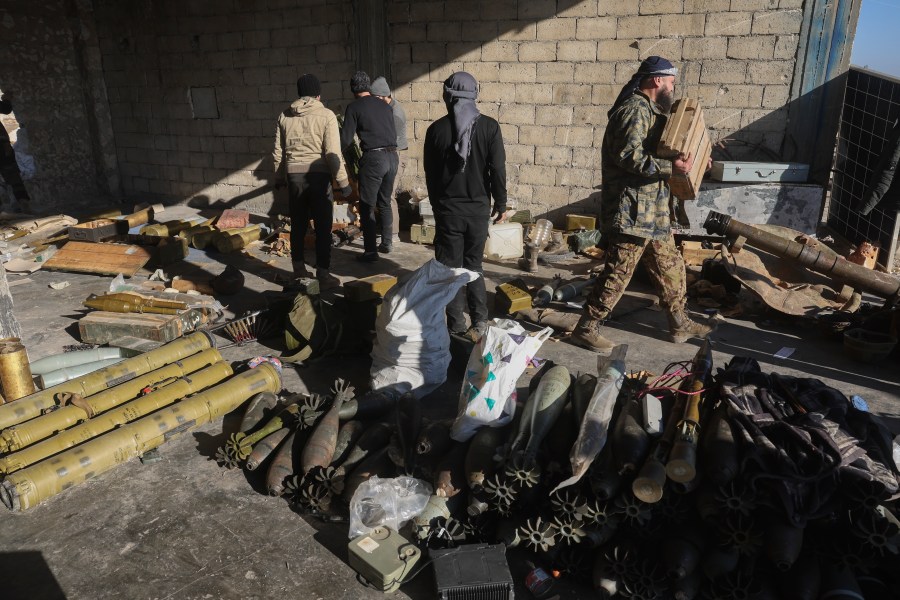 Syrian opposition fighters seize ammunition abandoned by the army in the town of Khan Assubul, Syria, southwest of Aleppo, Sunday, Dec. 1, 2024. Insurgents launched a two-pronged attack on Aleppo and the countryside around Idlib. (AP Photo/Ghaith Alsayed)