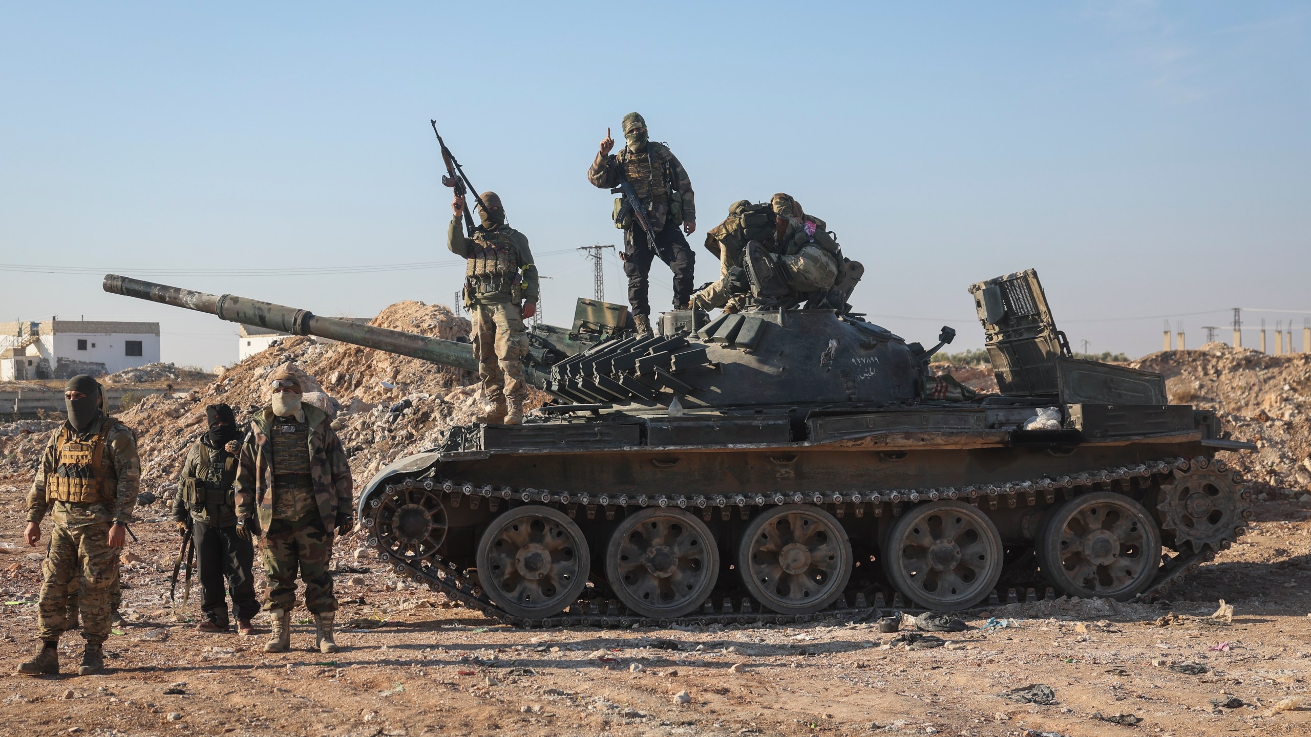 Syrian opposition fighters stand atop a seized Syrian army armoured vehicle in the outskirts of Hama, Syria, Tuesday Dec. 3, 2024. (AP Photo/Ghaith Alsayed)