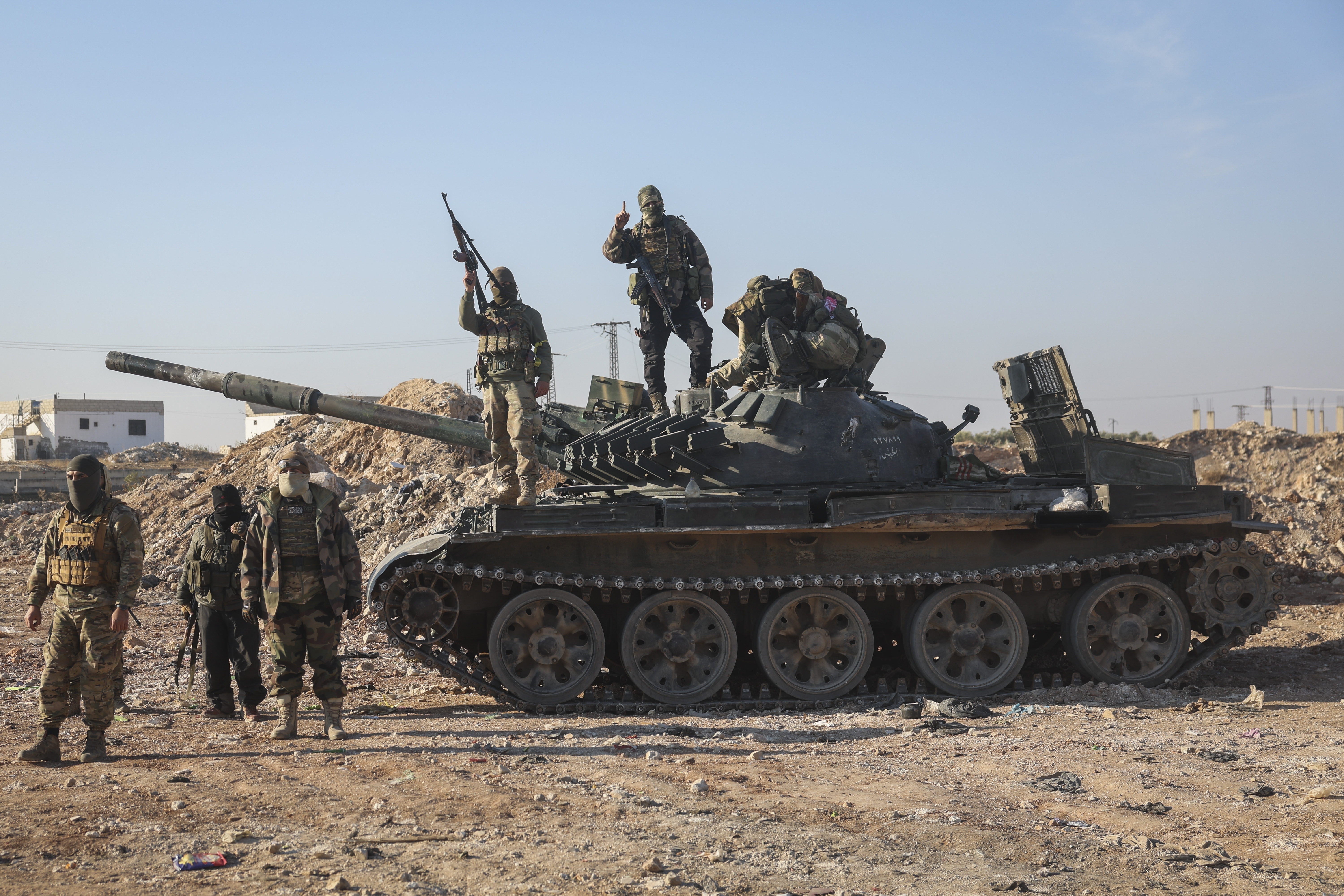 Syrian opposition fighters stand atop a seized Syrian army armoured vehicle in the outskirts of Hama, Syria, Tuesday Dec. 3, 2024. (AP Photo/Ghaith Alsayed)