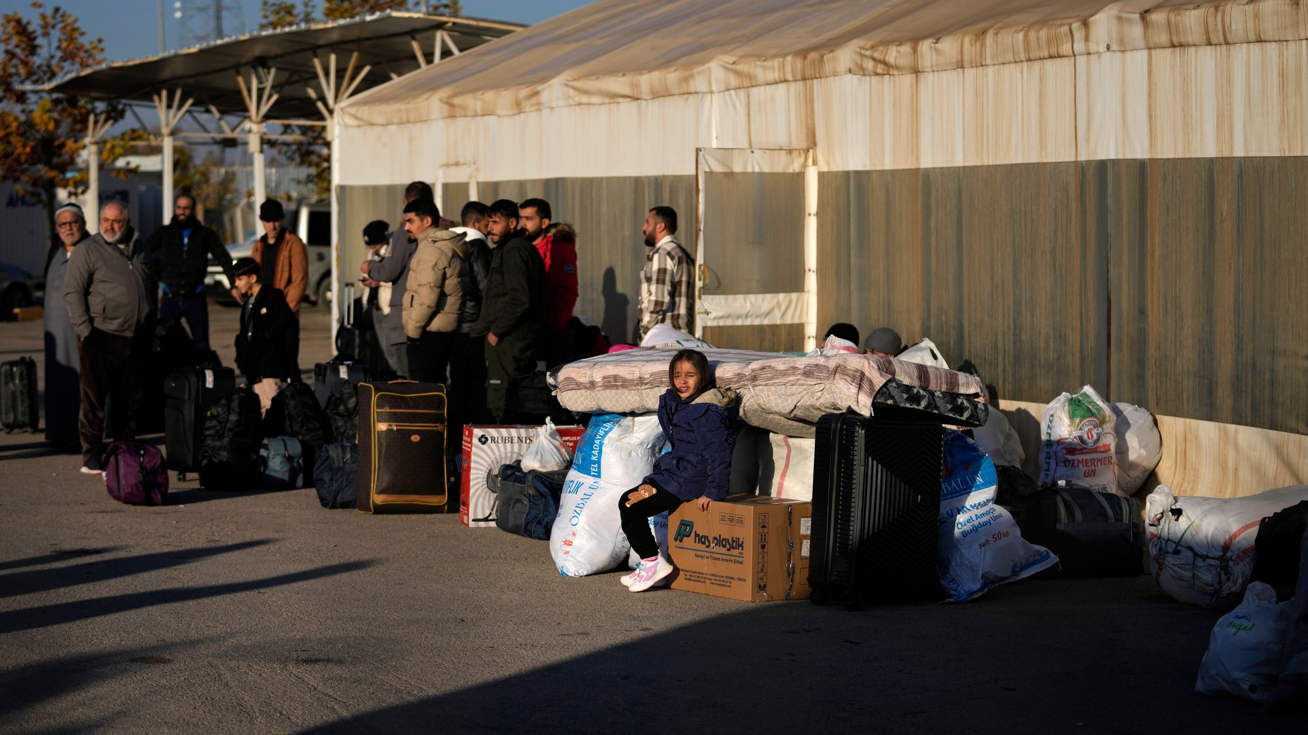 Syrians wait to cross into Syria from Turkey at the Oncupinar border gate, near the town of Kilis, southern Turkey, Monday, Dec. 9, 2024. (AP Photo/Khalil Hamra)