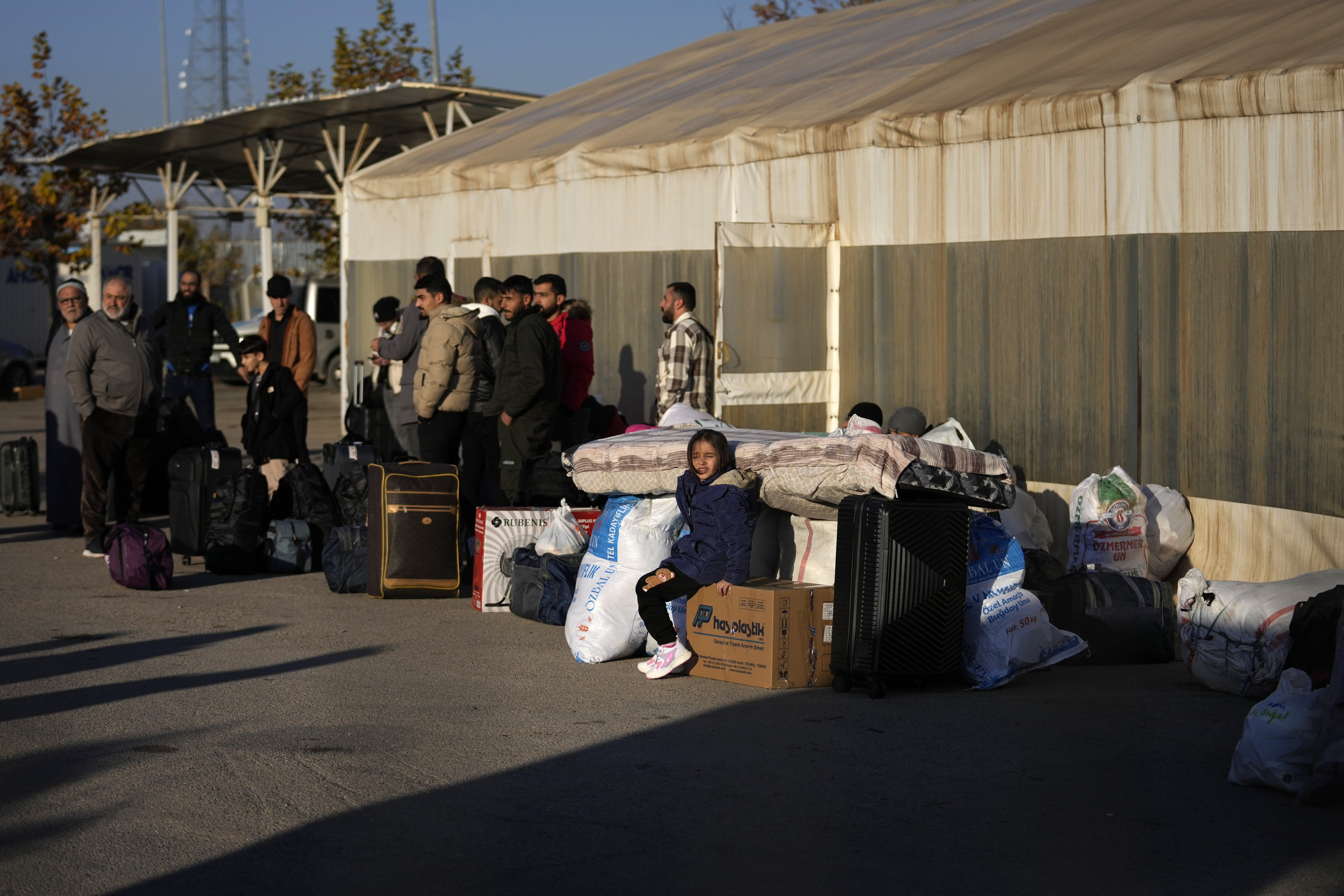 Syrians wait to cross into Syria from Turkey at the Oncupinar border gate, near the town of Kilis, southern Turkey, Monday, Dec. 9, 2024. (AP Photo/Khalil Hamra)