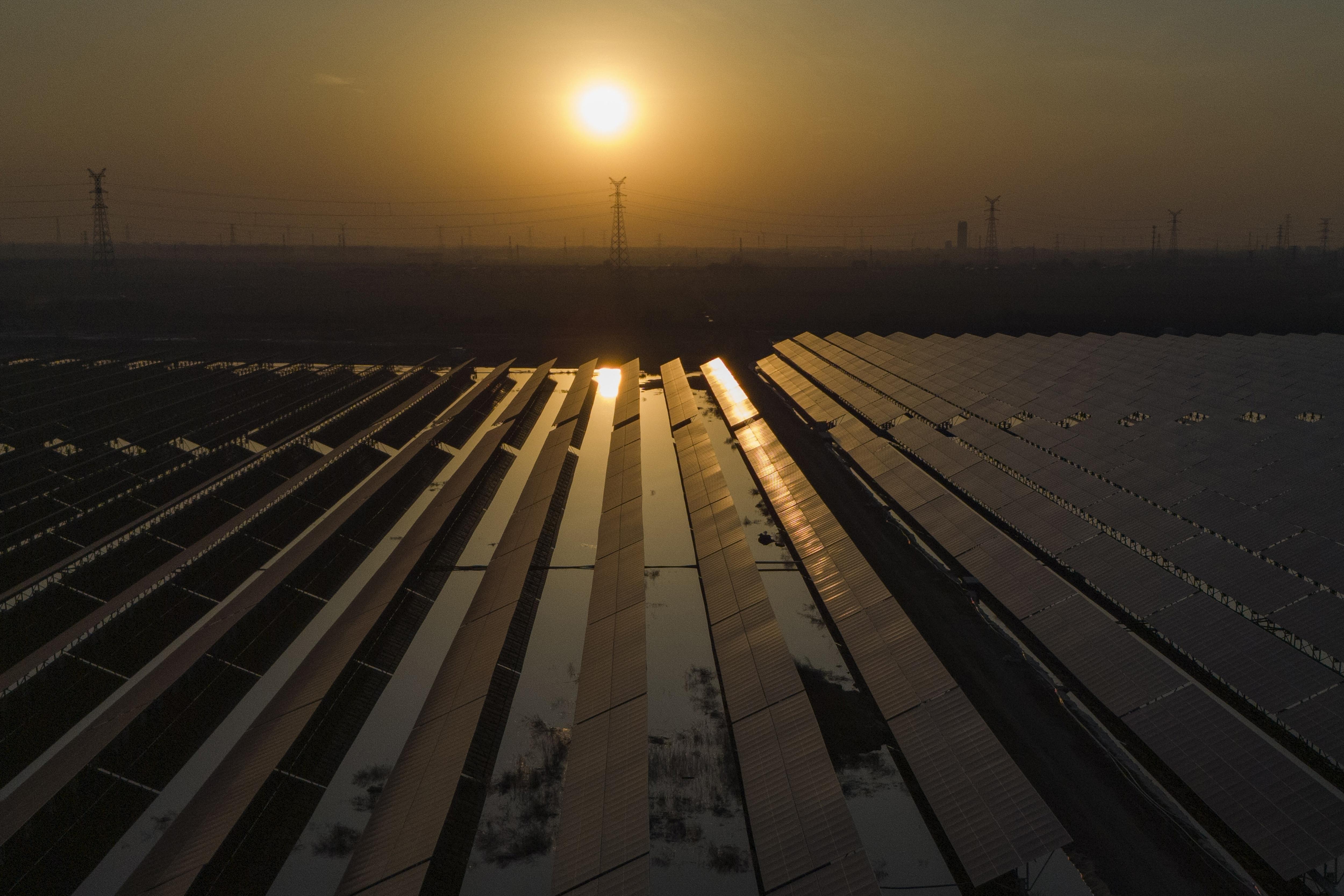 The sun sets over electric pylons along a solar farm near Weifang in eastern China's Shandong province on March 22, 2024. (AP Photo/Ng Han Guan)