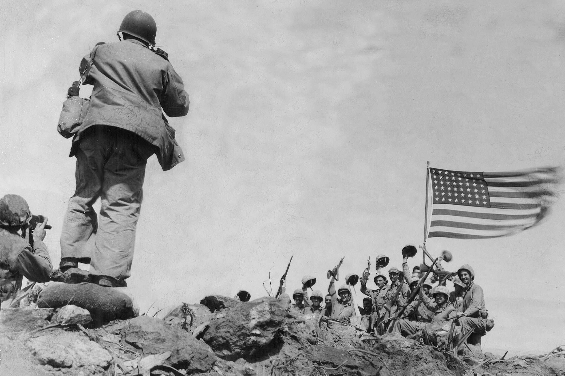 In this image provided by the U.S. Marine Corps, Marines of the 28th Regiment, 5th Division, AP photographer Joe Rosenthal photographs soldiers in front of the U.S. flag atop Mt. Suribachi, Iwo Jima, Japan, Feb. 23, 1945. (USMC/Pfc. Bob Campbell via AP)