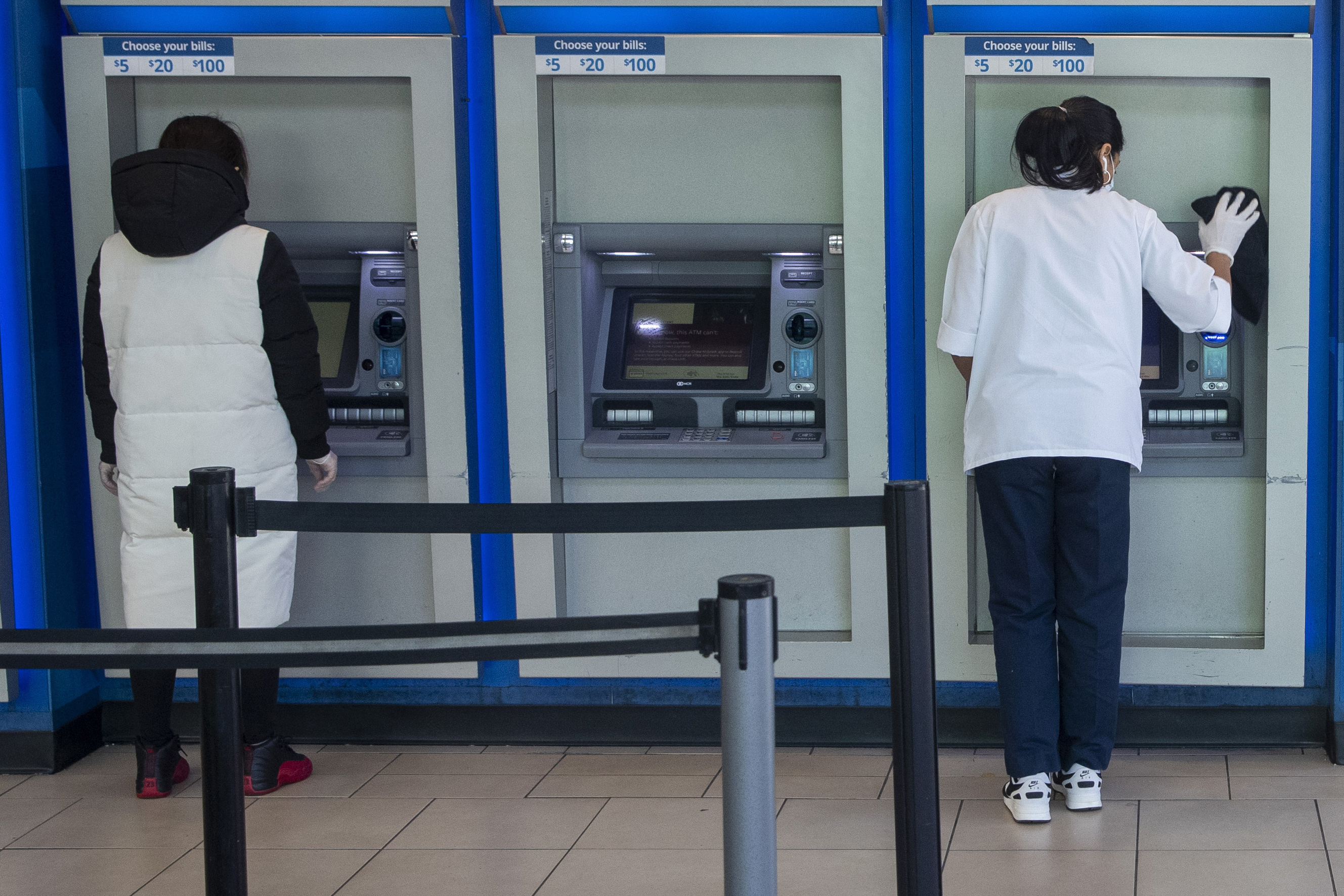 FILE - A customer makes a transaction at a bank of automatic teller machines in the Queens borough of New York on March 24, 2020. (AP Photo/Mary Altaffer, File)