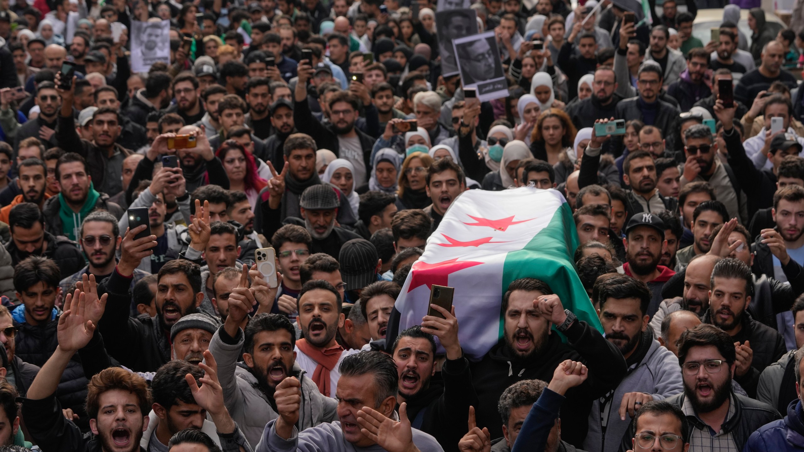 The coffin of Syrian activist Mazen al-Hamada is carried for burial in Damascus Thursday Dec. 12, 2024. Al-Hamad's mangled corpse was found wrapped in a bloody sheet in Saydnaya prison. He had fled to Europe but returned to Syria in 2020 and was imprisoned upon arrival. (AP Photo/Hussein Malla)