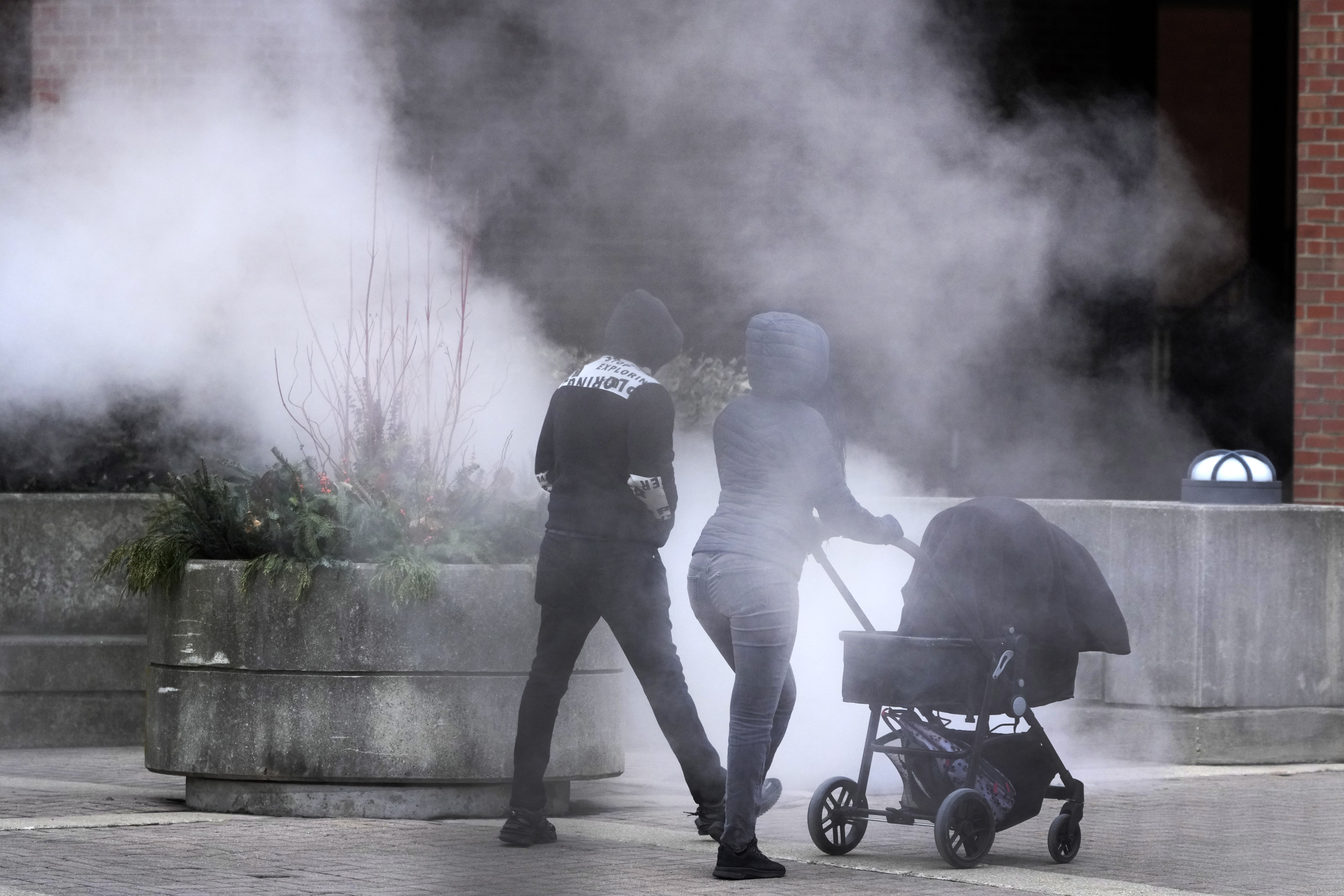 A couple push a baby carriage past steam released in the air as an Arctic blast brings single-digit temperatures with wind chills below zero on Thursday, Dec. 12, 2024, in Chicago. (AP Photo/Charles Rex Arbogast)