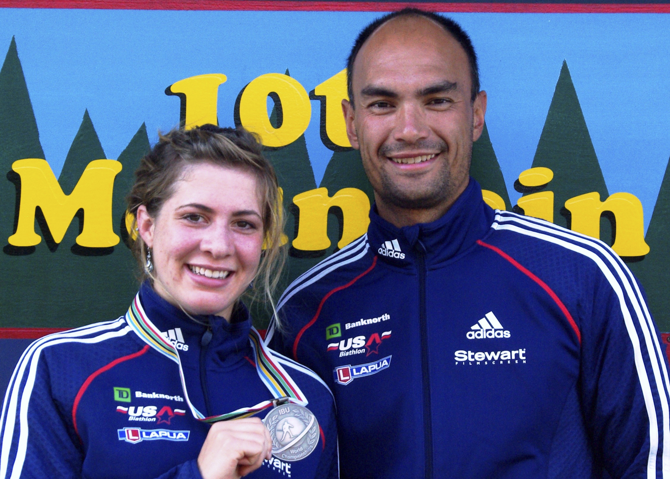 In this 2009 photo provided by Karen Gorman, biathlete Grace Boutot, left, of Fort Kent, Maine, displays her silver medal from the Youth Women Biathlon World Championships, while standing with coach Gary Colliander, right, in Fort Kent. (Karen Gorman via AP)