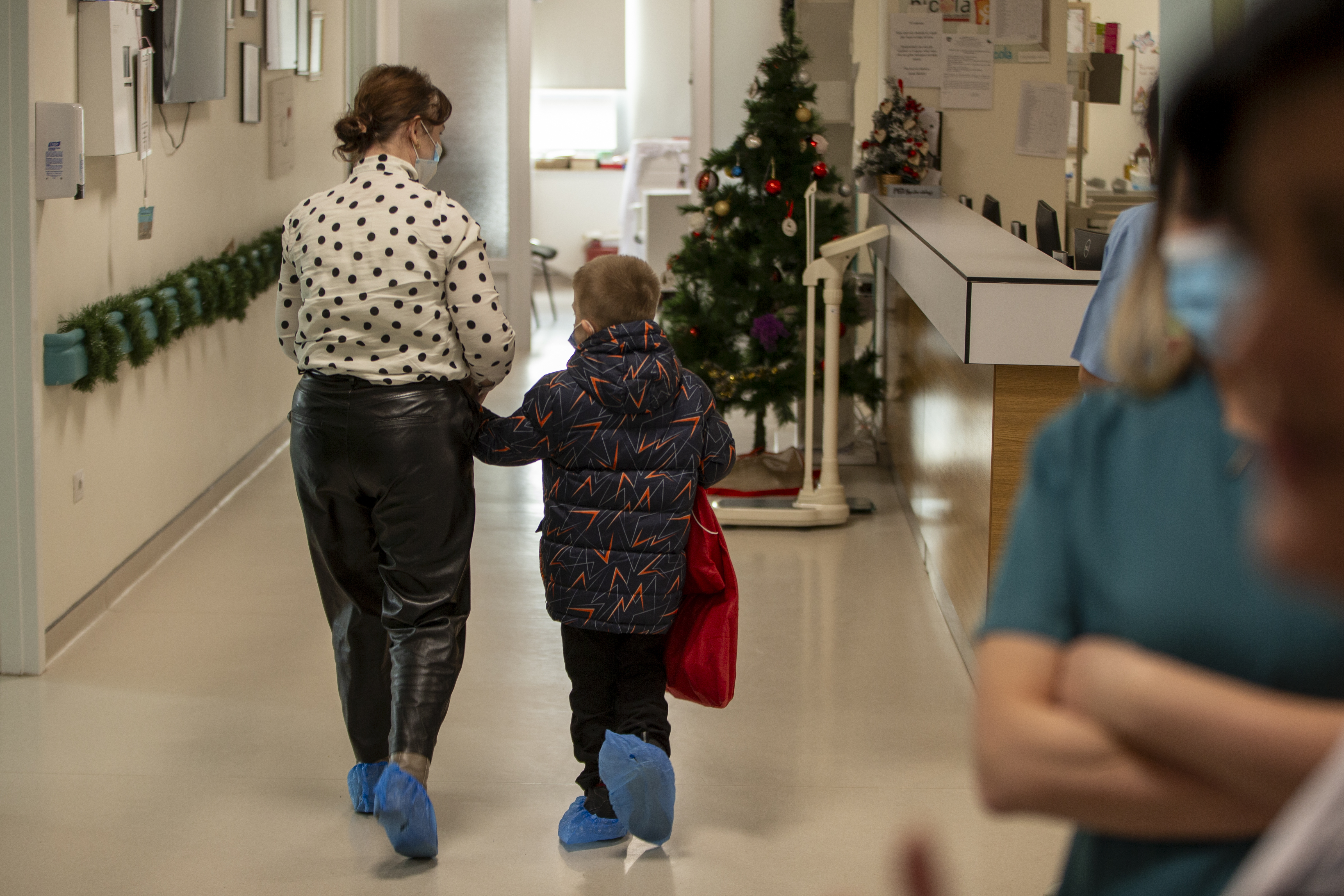 A patient with his mother walks back to his room after Kosovo alpinists disguised as super-heroes brought gifts in Pristina hospital on Friday, Dec. 13, 2024. (AP Photo/Visar Kryeziu)