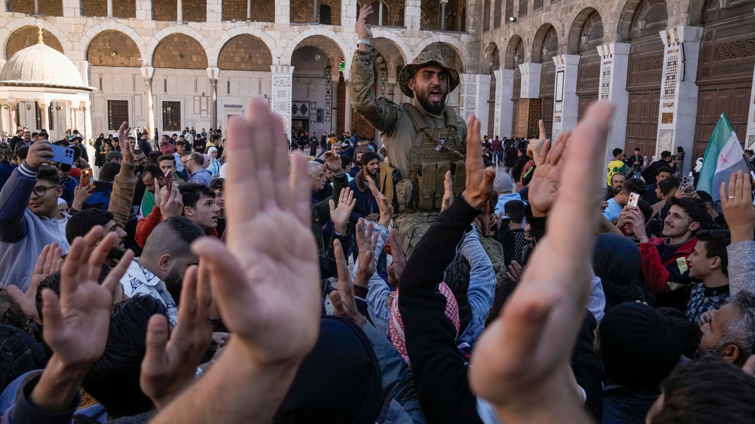 Syrians fighters and civilians chant slogans as they gather for Friday prayers at the Umayyad mosque in Damascus, Syria, Friday, Dec. 13, 2024. (AP Photo/Leo Correa)