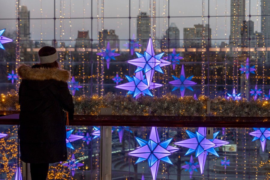 A person views lights in front of the New York skyline at The Shops at Columbus Circle, Thursday, Dec. 12, 2024, in New York. (AP Photo/Julia Demaree Nikhinson)