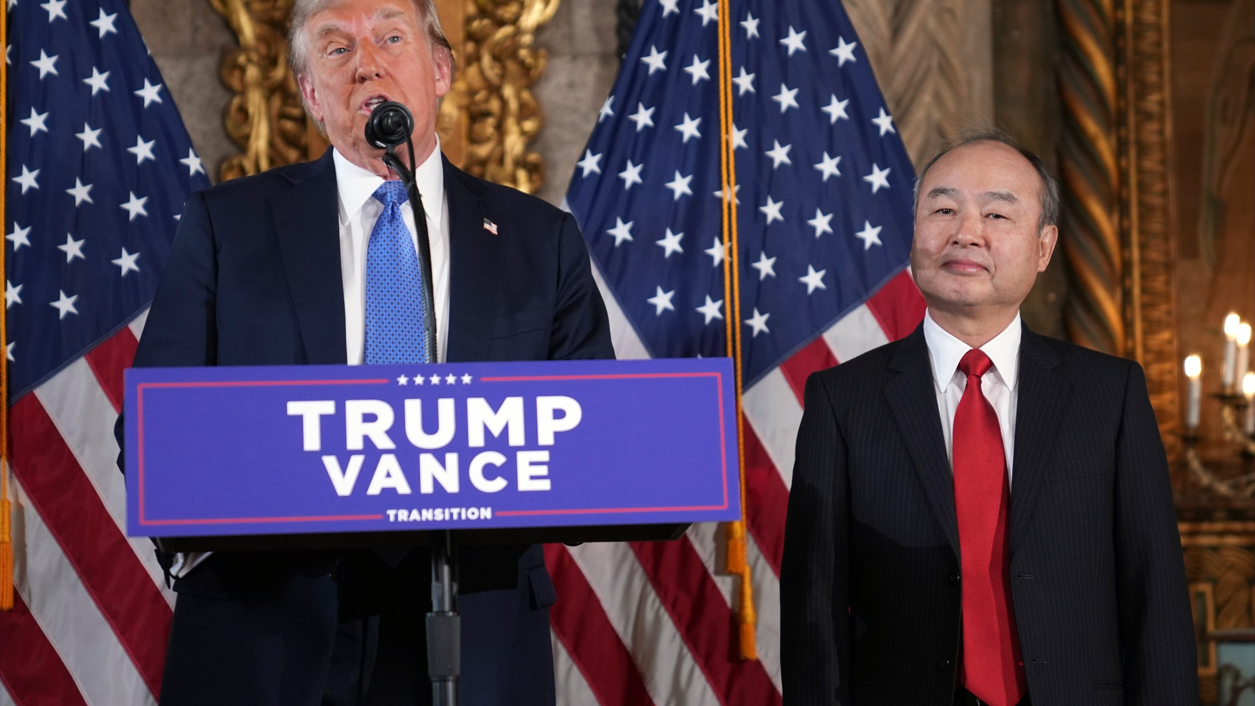 President-elect Donald Trump speaks during a news conference at Mar-a-Lago, Monday, Dec. 16, 2024, in Palm Beach, Fla., as SoftBank Group CEO Masayoshi Son listens. (AP Photo/Evan Vucci)