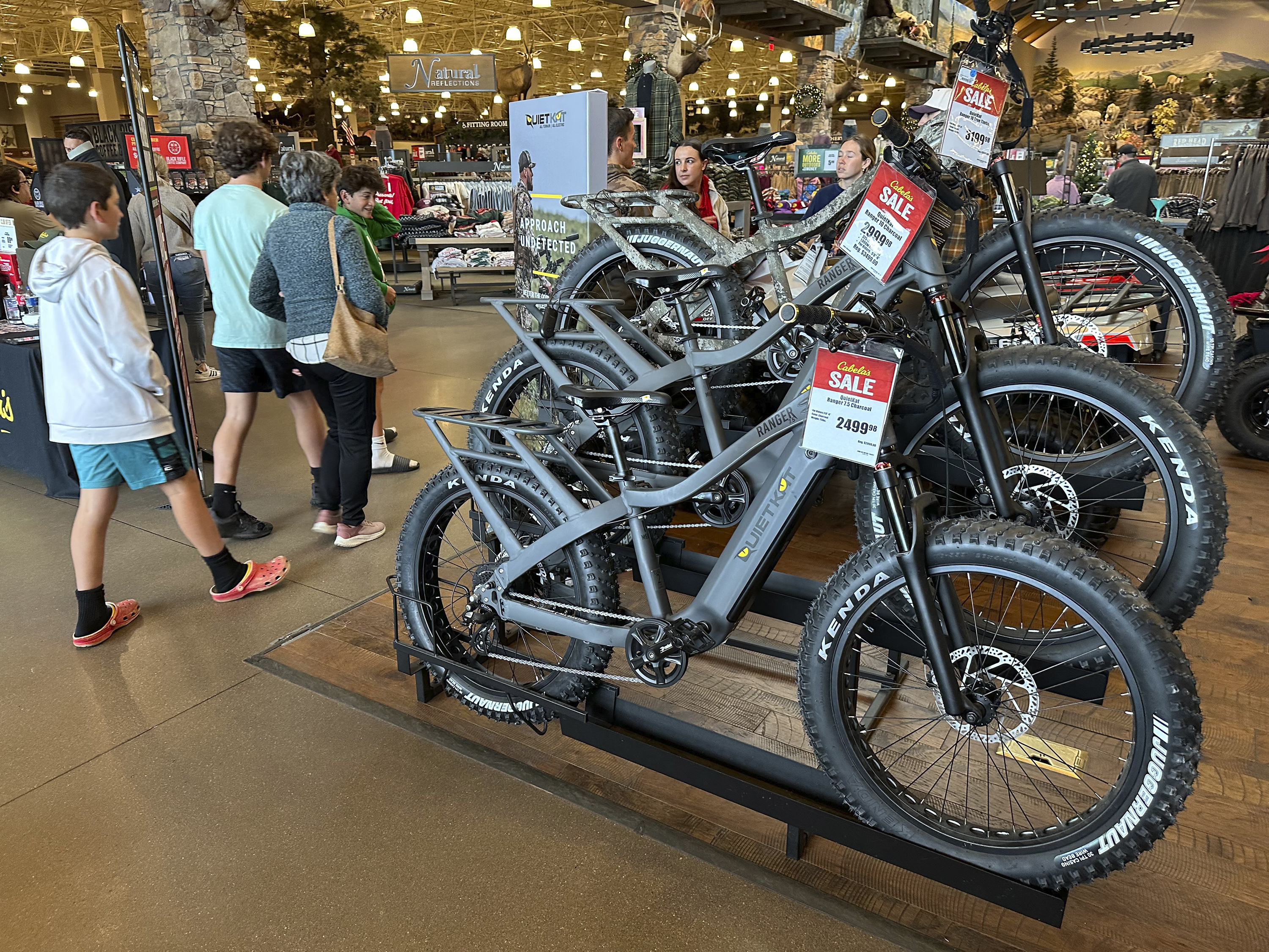 Shoppers pass by electric bicycles on display in a Cabela's sporting goods store Sunday, Dec. 8, 2024, in Lone Tree, Colo. (AP Photo/David Zalubowski)