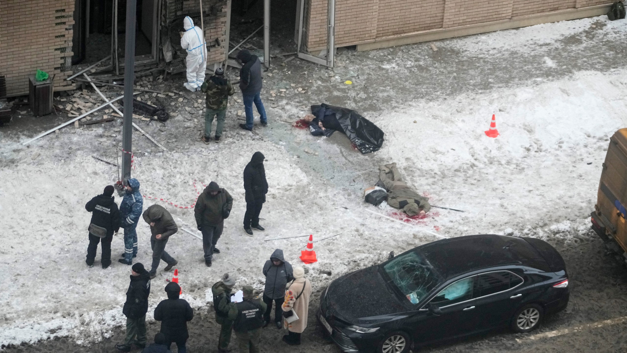 EDS NOTE: GRAPHIC CONTENT - Investigators work at the place where Lt. General Igor Kirillov, center, the head of Russia's Nuclear, Biological, and Chemical Defence Forces and his assistant, right, were killed by an explosive device planted close to a residential apartment's block in Moscow, Russia, Tuesday, Dec. 17, 2024. (AP Photo)