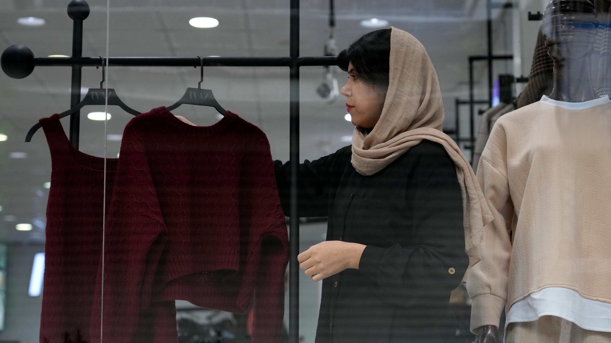 A shopkeeper puts on a woman's clothes on a mannequin at a shop in port city of Bandar Anzali in northern Iran, Thursday, Dec. 5, 2024. (AP Photo/Vahid Salemi)