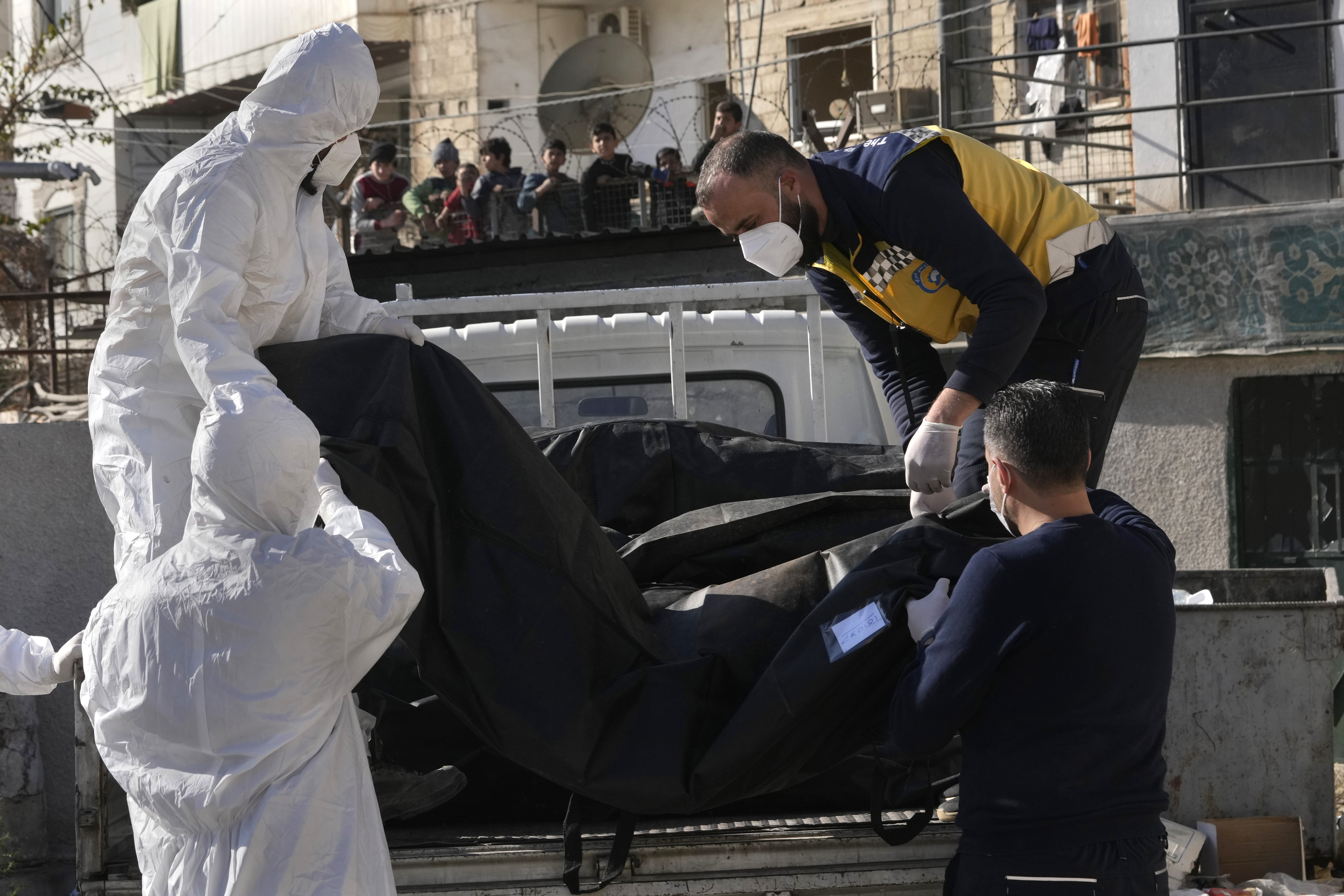 Members of the Syrian civil defense group, known as the White Helmets, put on a truck bodies and human remains after they collect them from a morgue, previously used by pro-government Iranian units, located near the Set Zainab shrine, south of Damascus, Syria, Wednesday, Dec. 18, 2024. (AP Photo/Hussein Malla)