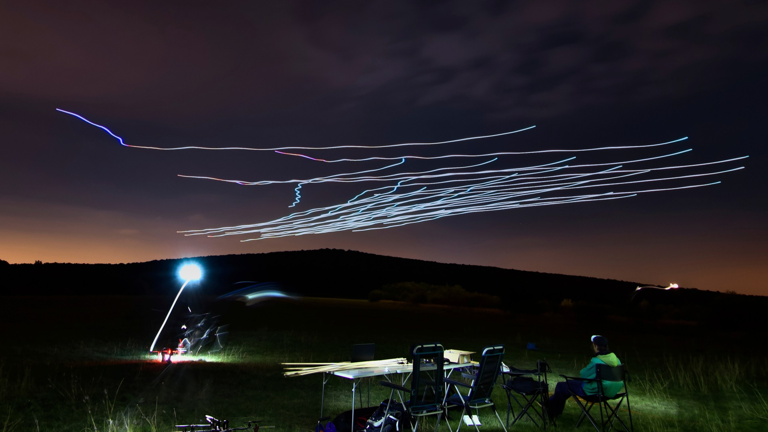 This handout photo taken with long exposure shows a researcher of the Eötvös Loránd University observing the flight of a flock of autonomous drones during an experiment near Budapest, Hungary, Thursday, Oct. 21, 2021. (AP Photo/HO/Eotvos Lorand University)