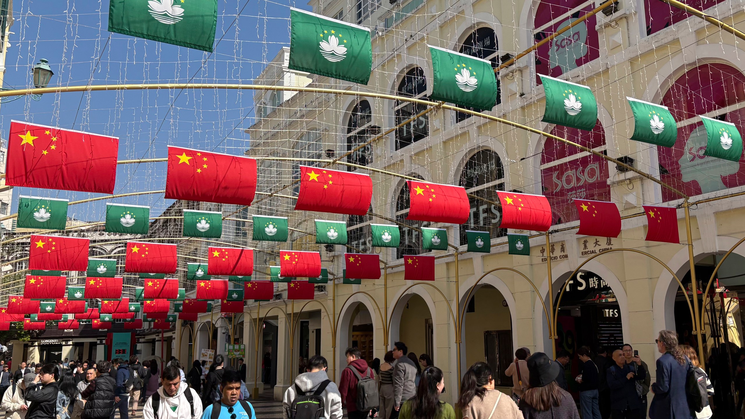 Tourists walk past a street decorated with Chinese national flags and Macao regional flags in Macao on Dec. 13, 2024. (AP Photo/Kanis Leung)