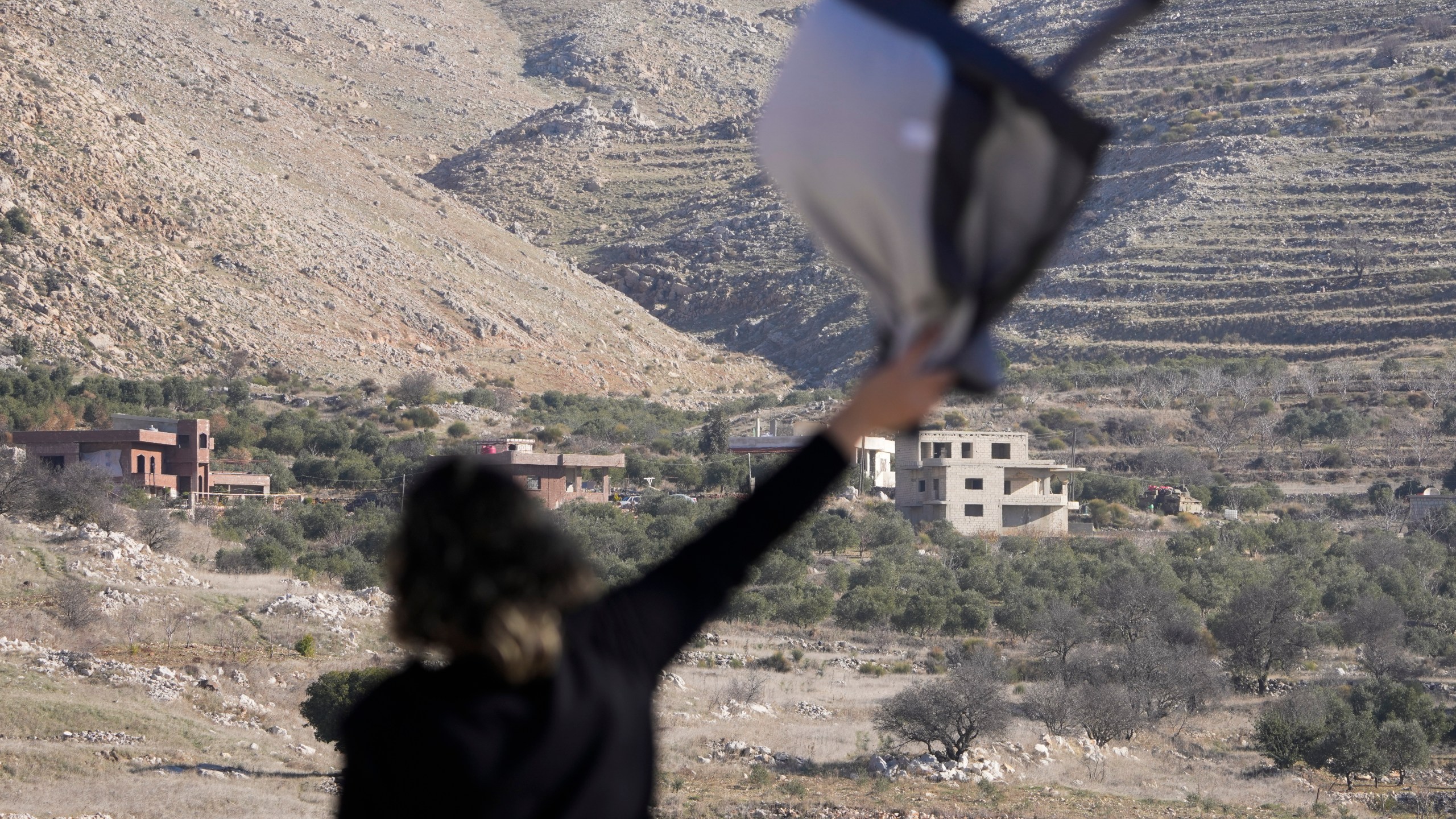 Salma Safadi waves to her sister, Sawsan, who is inside the buffer zone near the "Alpha Line" that separates the Israeli-controlled Golan Heights from Syria, in the town of Majdal Shams, Tuesday, Dec. 17, 2024. (AP Photo/Matias Delacroix)