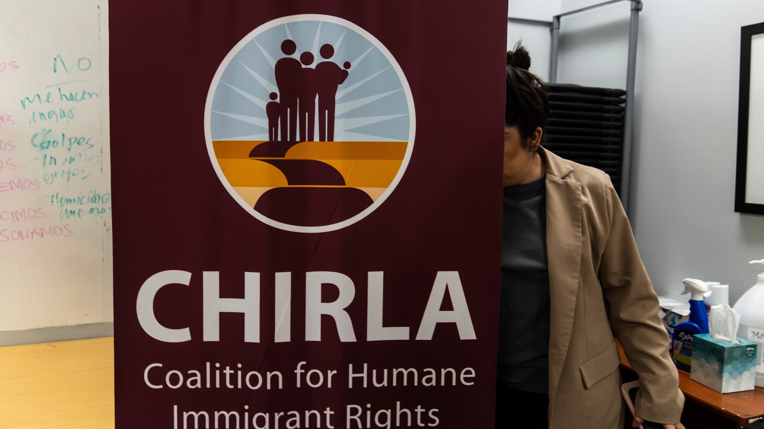 Elizabeth Rodriguez, digital content creator at the Coalition for Humane Immigrant Rights, sets up a banner for a bilingual workshop for immigrants who want to stay in the United States in Los Angeles, Wednesday, Dec. 4, 2024. (AP Photo/Jae C. Hong)