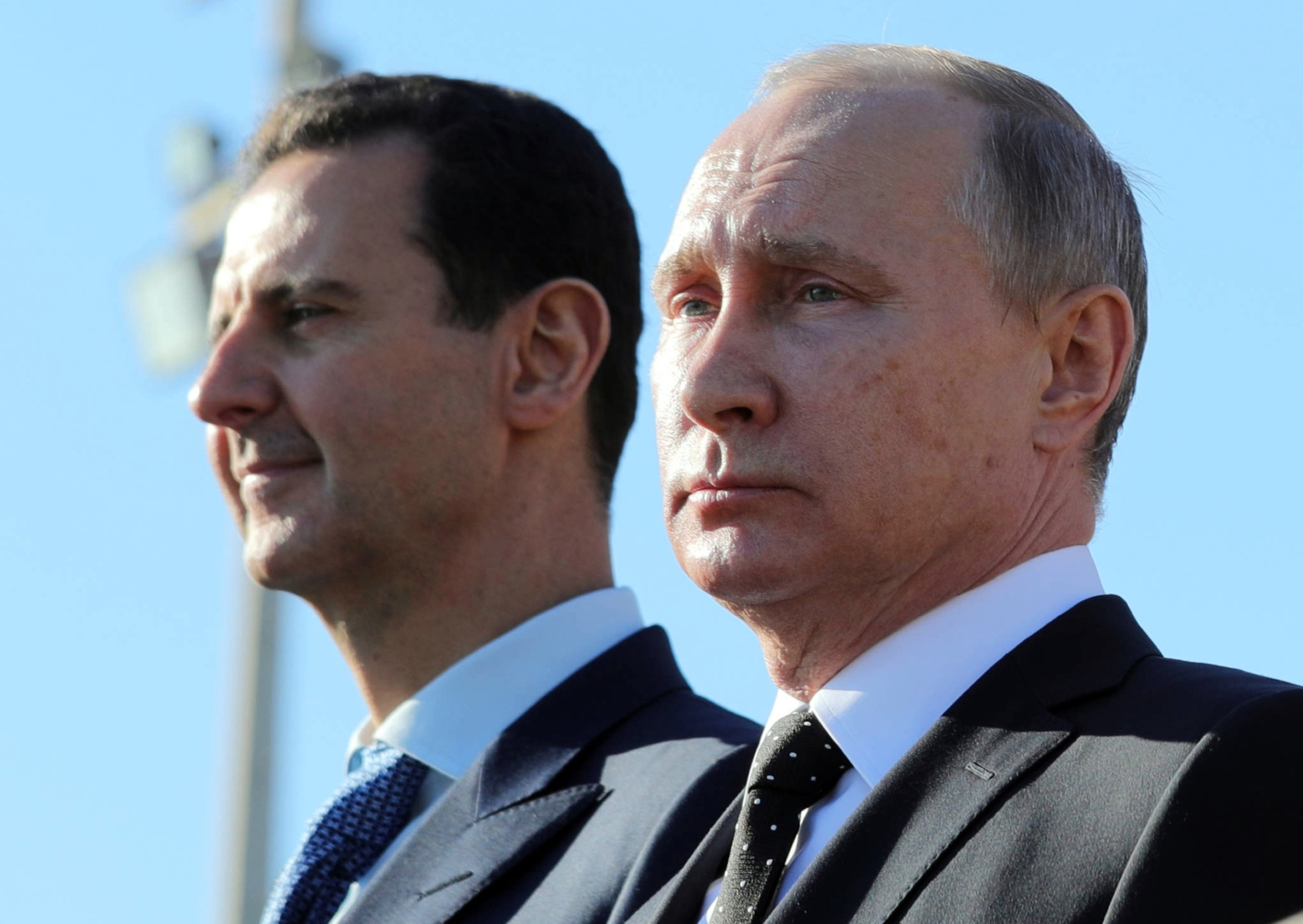 FILE - Russian President Vladimir Putin, right, and Syrian President Bashar Assad watch troops at the Hemeimeem air base in Syria, on Dec. 11, 2017. (Mikhail Klimentyev, Sputnik, Kremlin Pool Photo via AP, File)