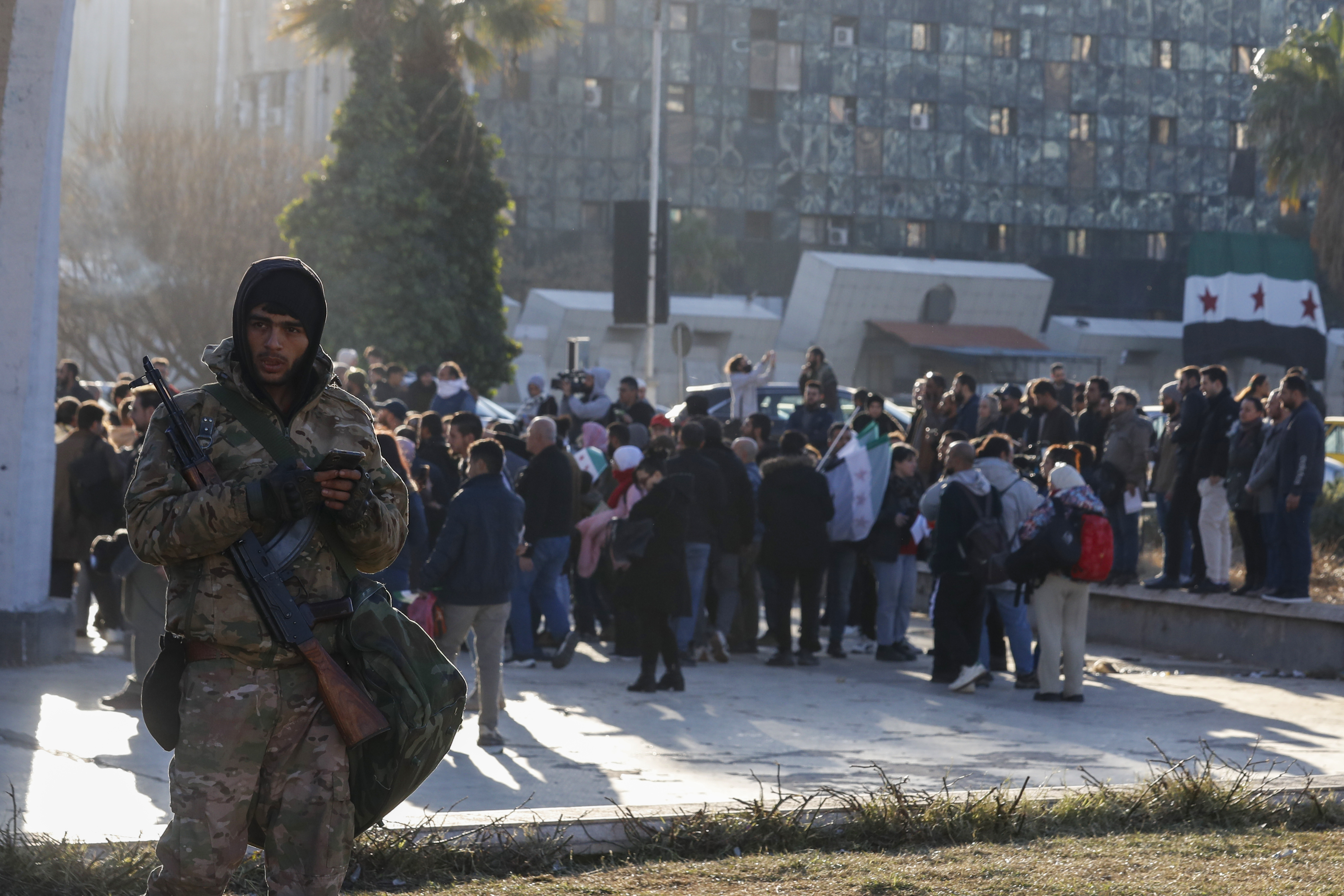 A Syrian fighter stands guard as activists gather at the Umayyad square during a protest to demand a secular state, in Damascus, Syria, Thursday, Dec. 19, 2024. (AP Photo/Omar Sanadiki)