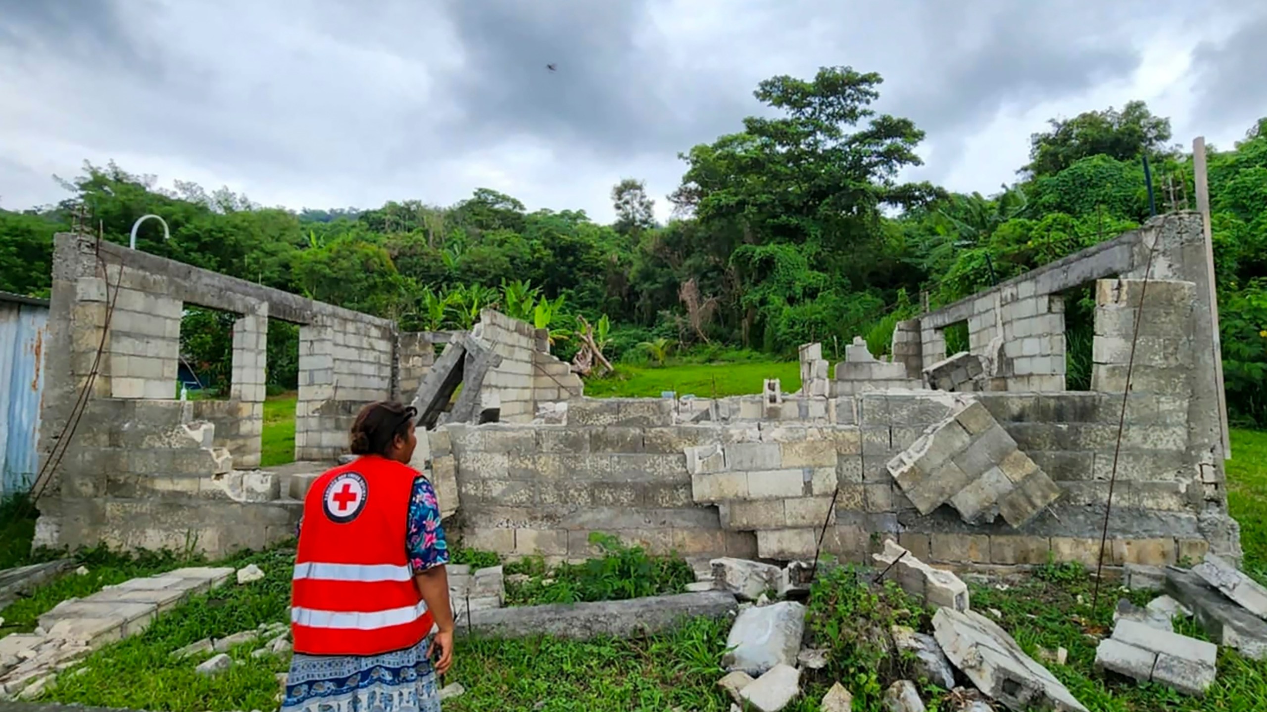 In this photo released by Vanuatu Red Cross Society, a Red Cross volunteer inspects a damaged house in Efate, Vanuatu, Thursday, Dec. 19, 2024, following a powerful earthquake that struck just off the coast of Vanuatu in the South Pacific Ocean. (Vanuatu Red Cross Society via AP)