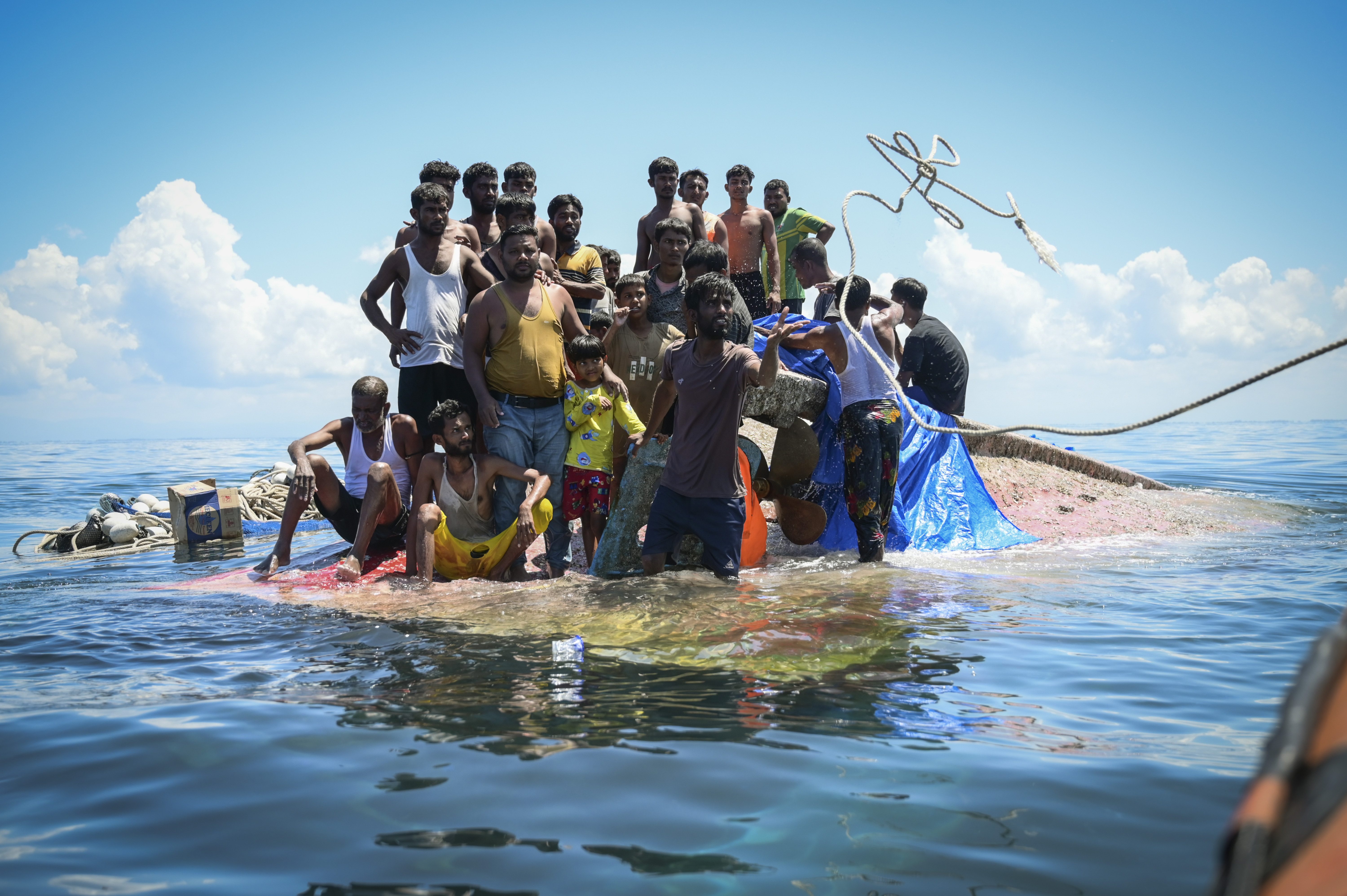 Ethnic Rohingya refugees stand on their capsized boat as rescuers throw a rope to them off West Aceh, Indonesia, on March 21, 2024. (AP Photo/Reza Saifullah)